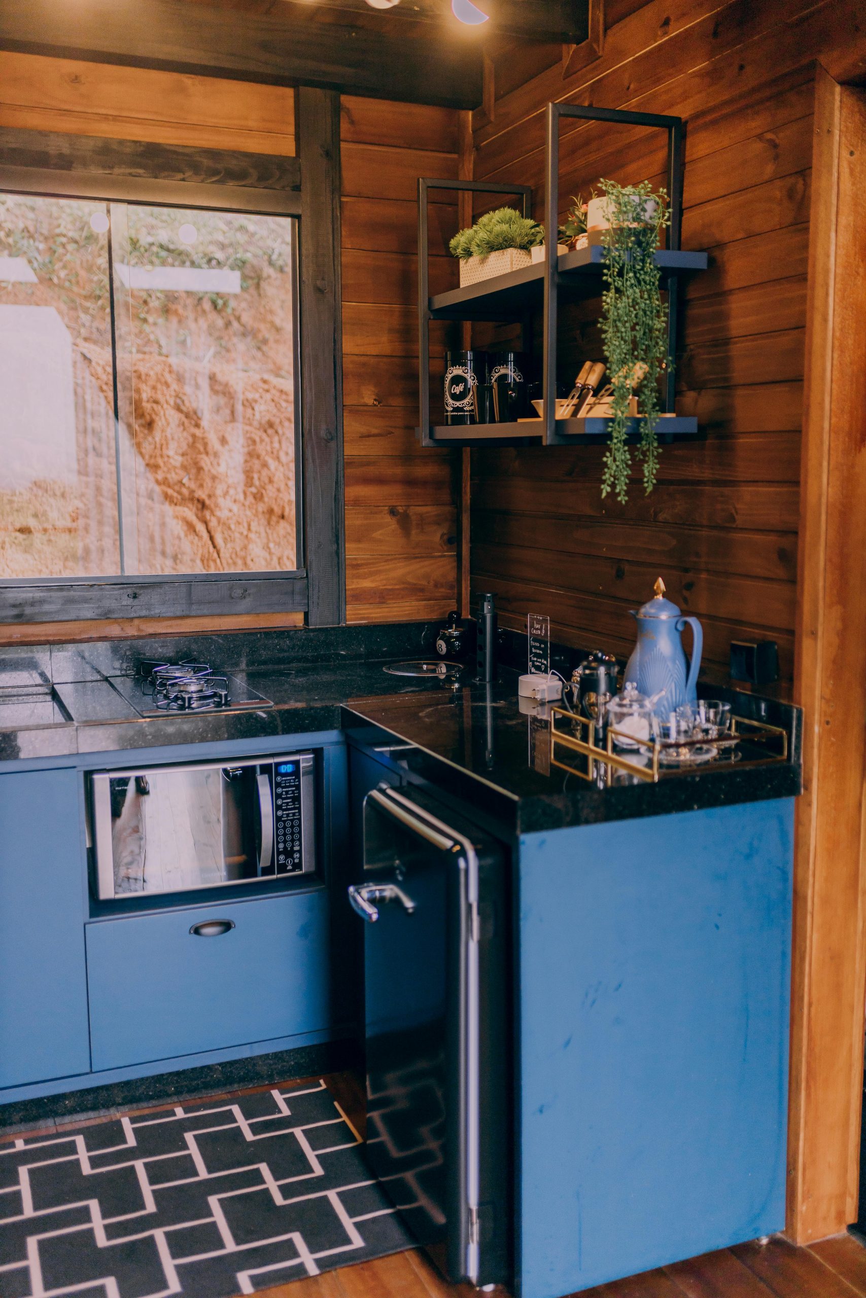 A modern kitchen featuring blue cabinets, sleek appliances, and wooden walls, perfect for interior design inspiration.