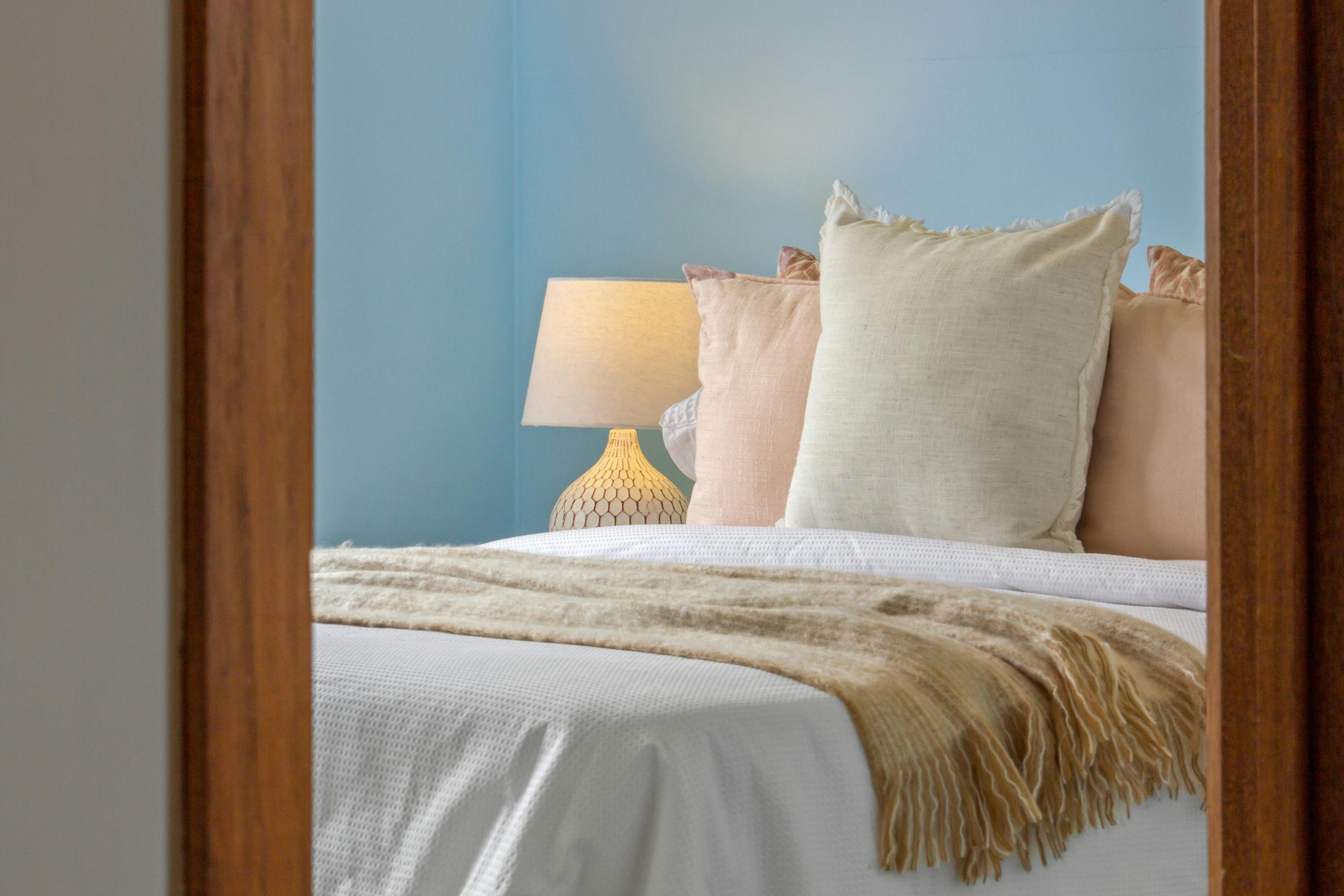A serene bedroom scene featuring blue walls, decorative pillows, and soft lighting for a cozy ambiance.