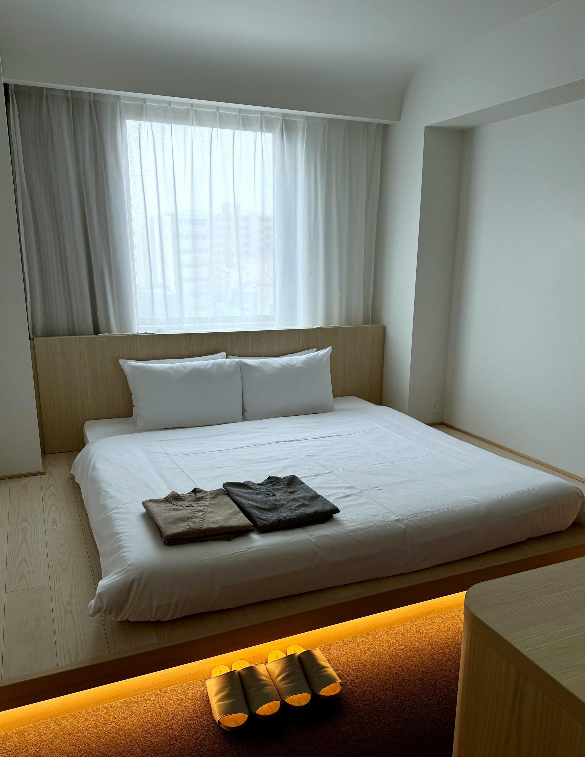 A serene minimalist bedroom with natural light and Japanese-style design elements.