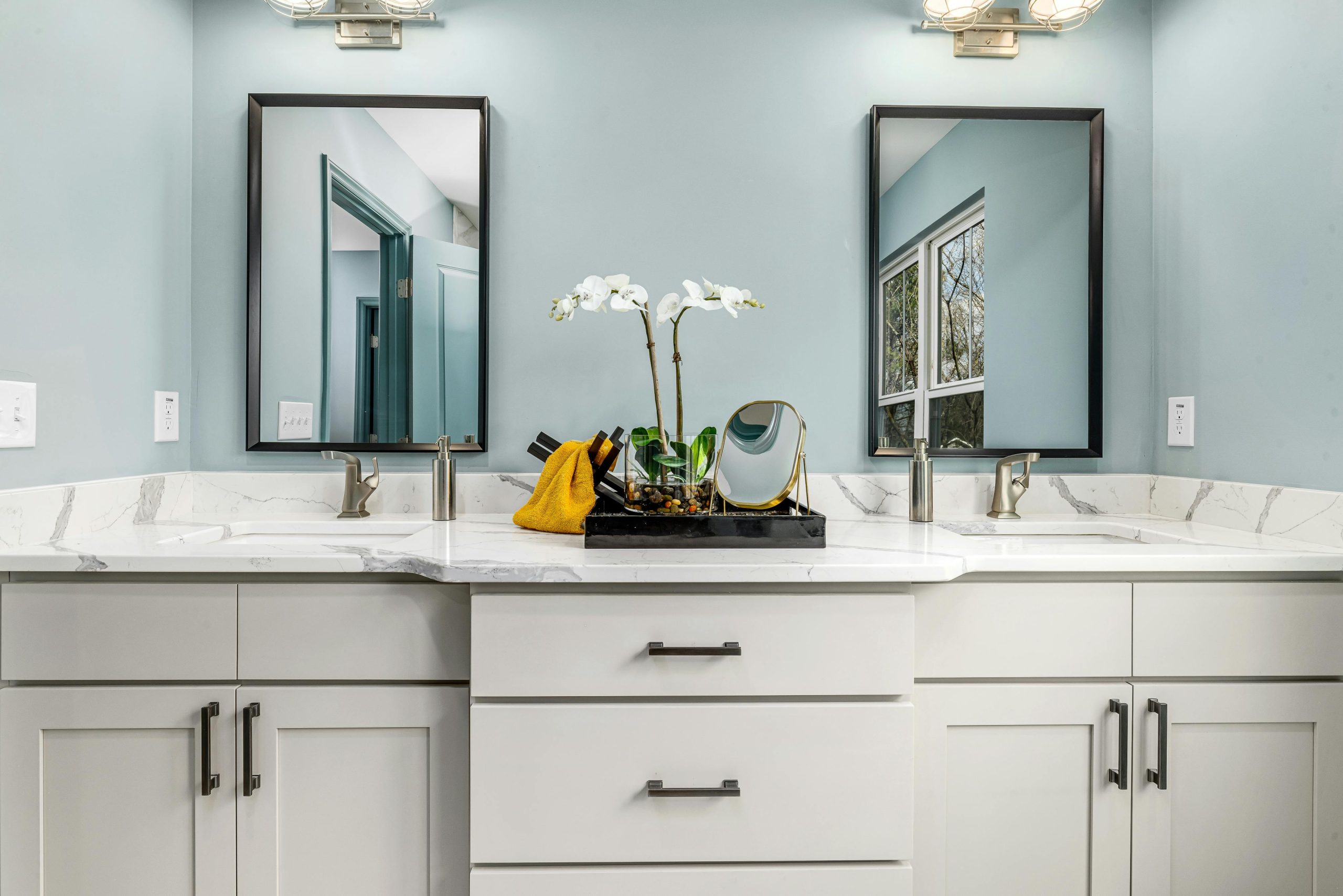 A serene modern bathroom featuring twin sinks, elegant faucets, and decorative mirrors.
