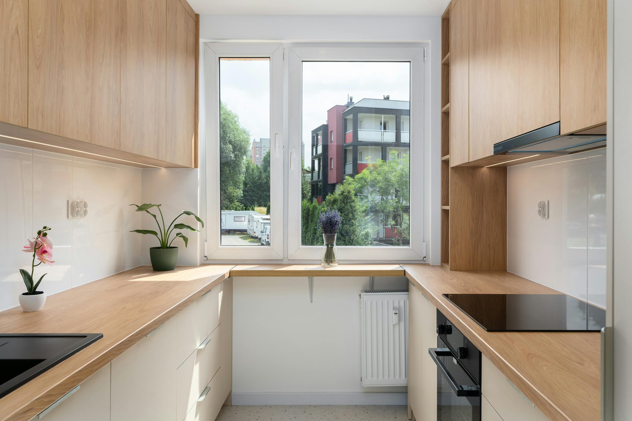A sleek and contemporary kitchen with natural wood accents and a city view through the large window.