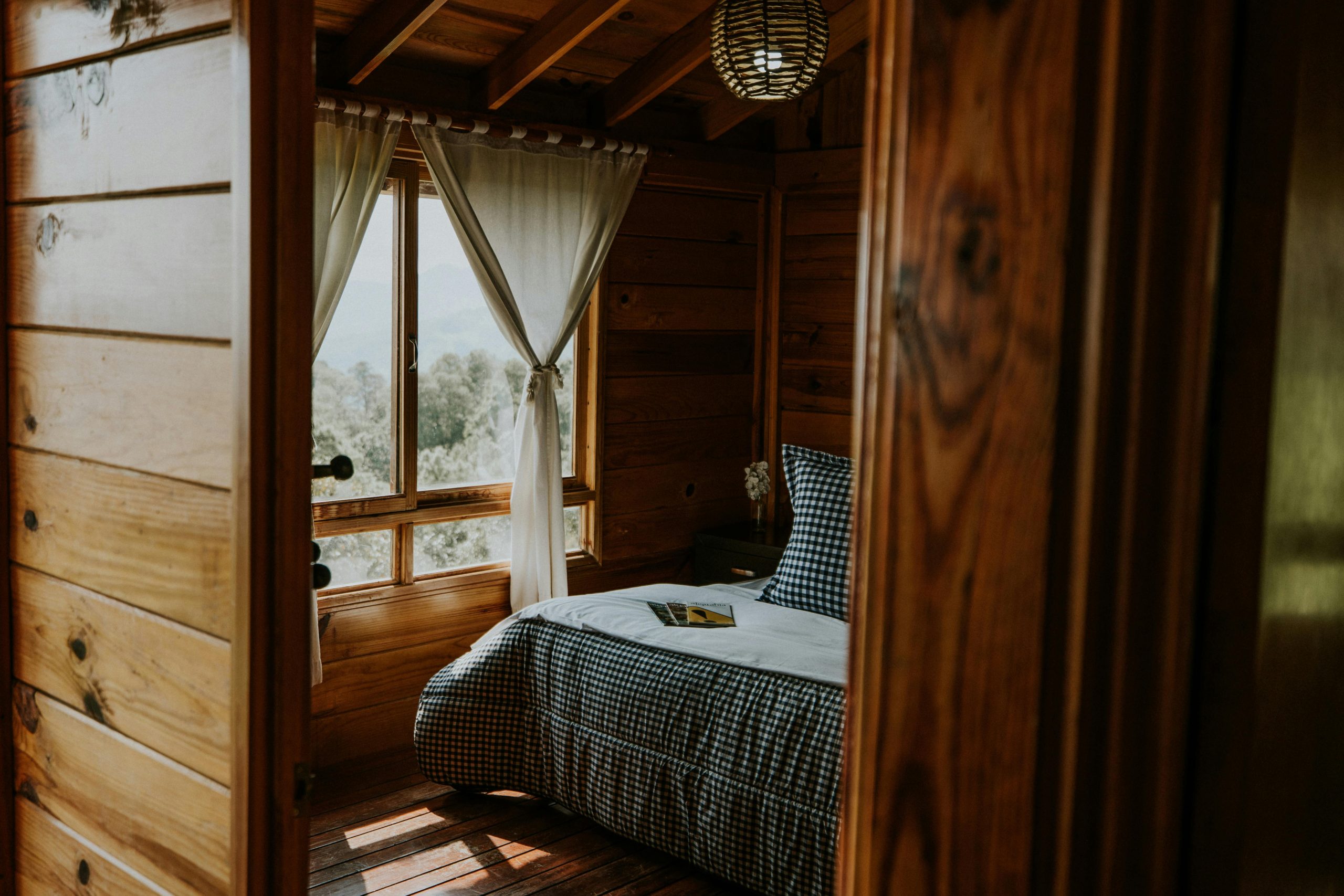 A warm and inviting wooden cabin bedroom with mountain views, ideal for relaxation.
