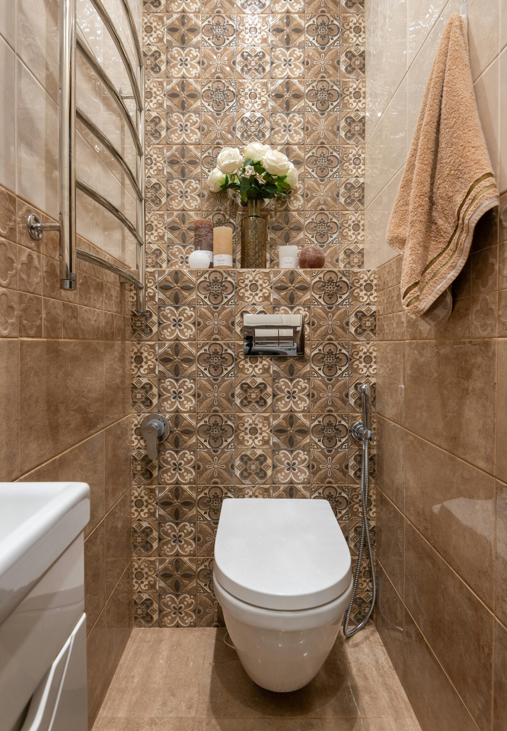 An elegantly designed bathroom showcasing a ceramic toilet and floral tiled wall with decorative elements.
