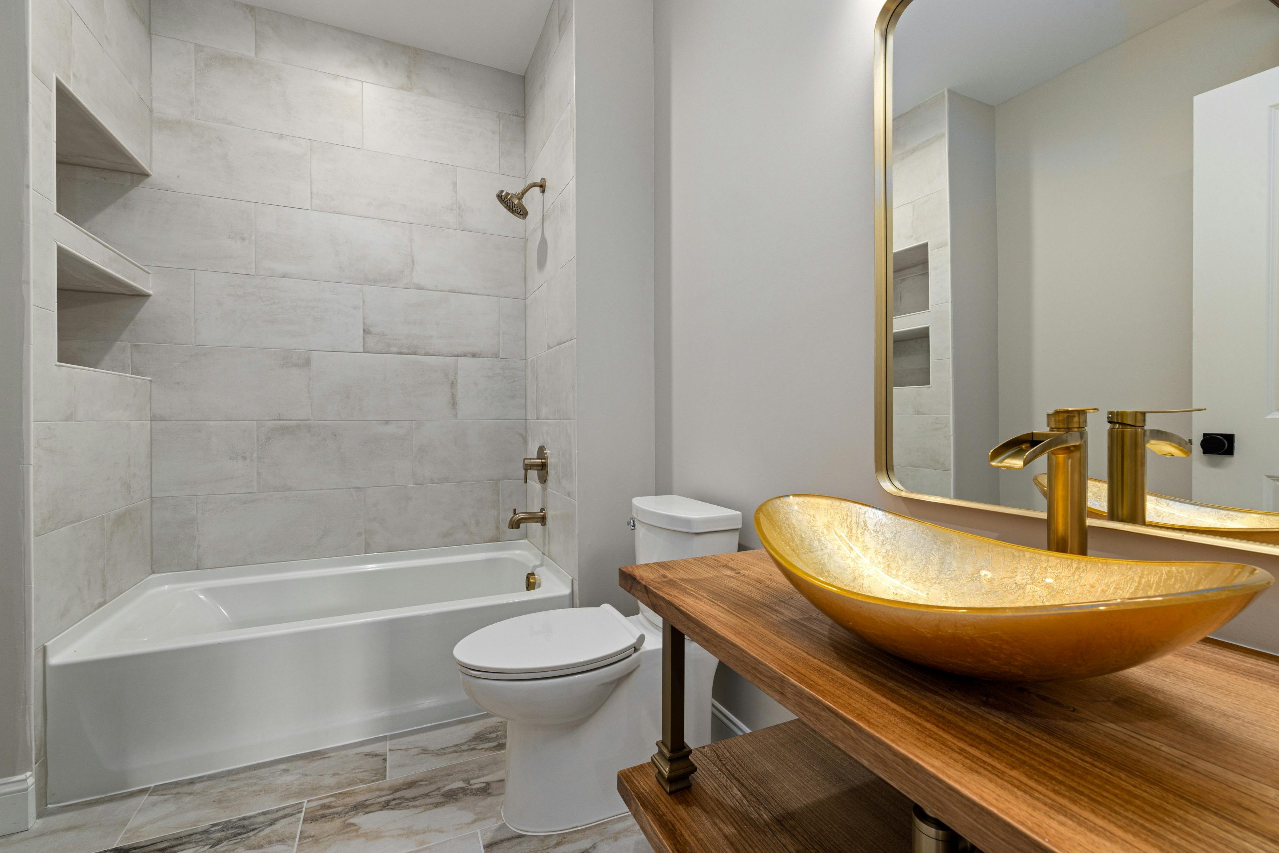 Bright and elegant bathroom featuring a designer gold basin, marble tiles, and classic fixtures.