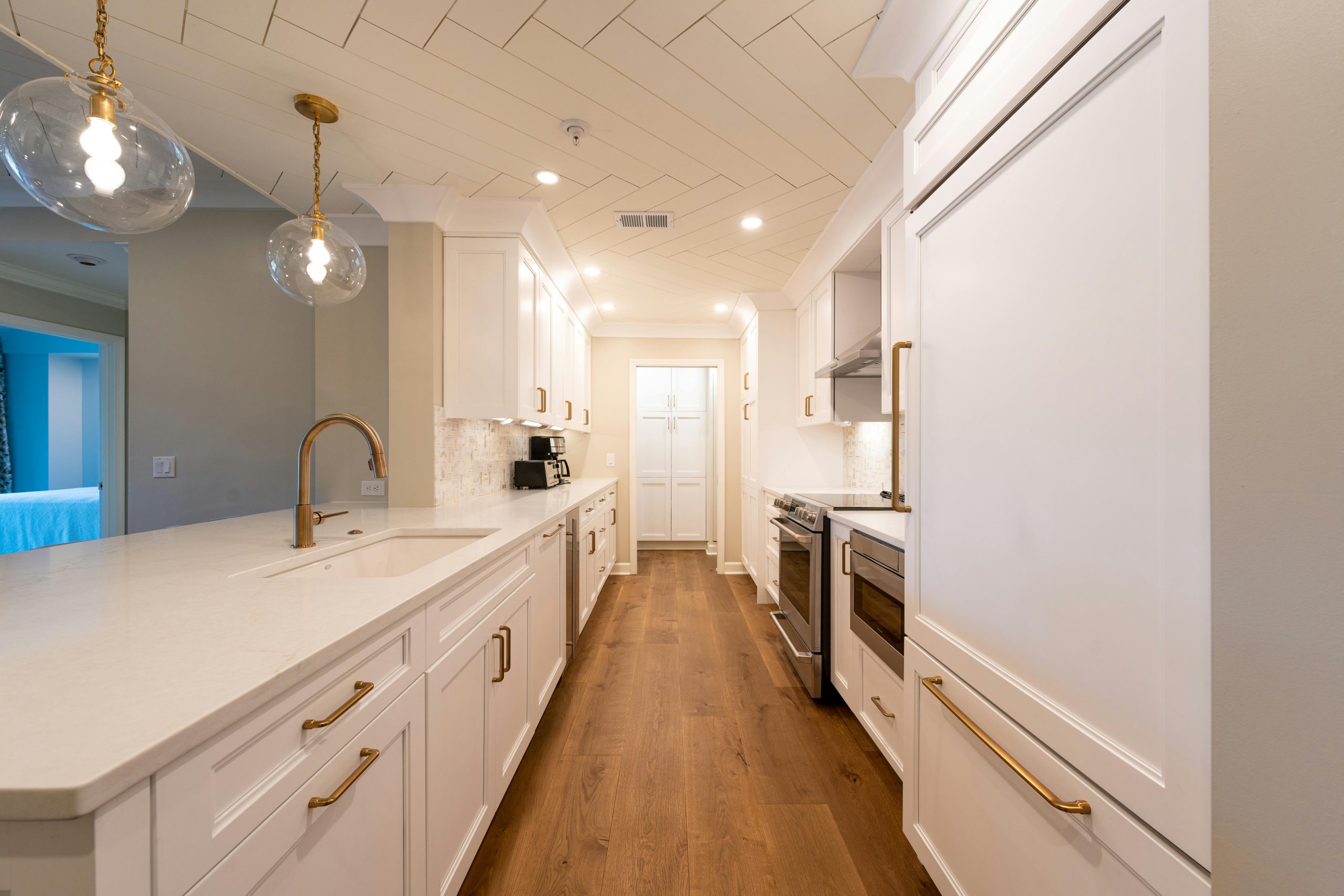 Bright and spacious modern white kitchen with gold accents and elegant lighting, showcasing contemporary design details.