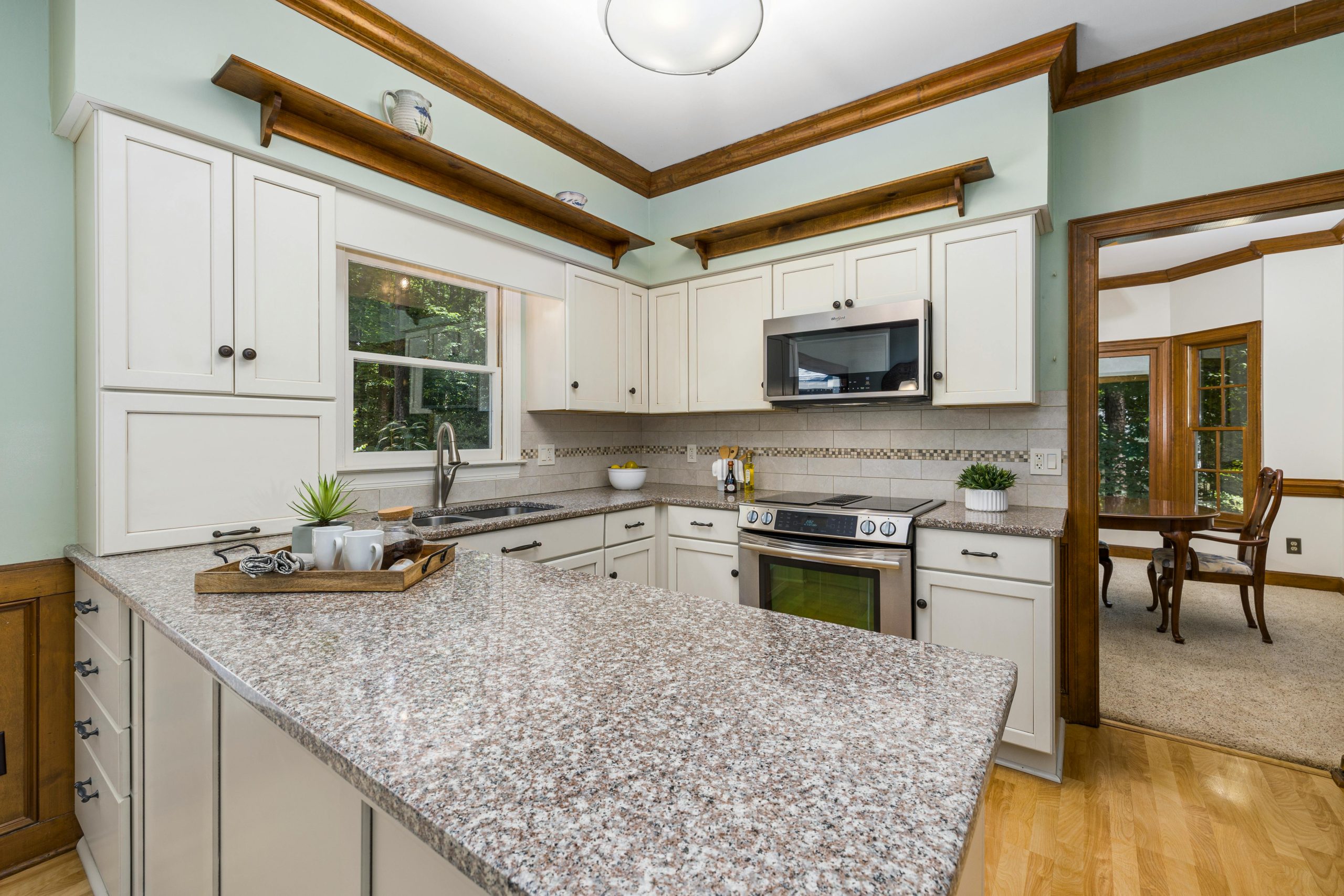 Bright kitchen featuring granite countertops, white cabinetry, and modern appliances.