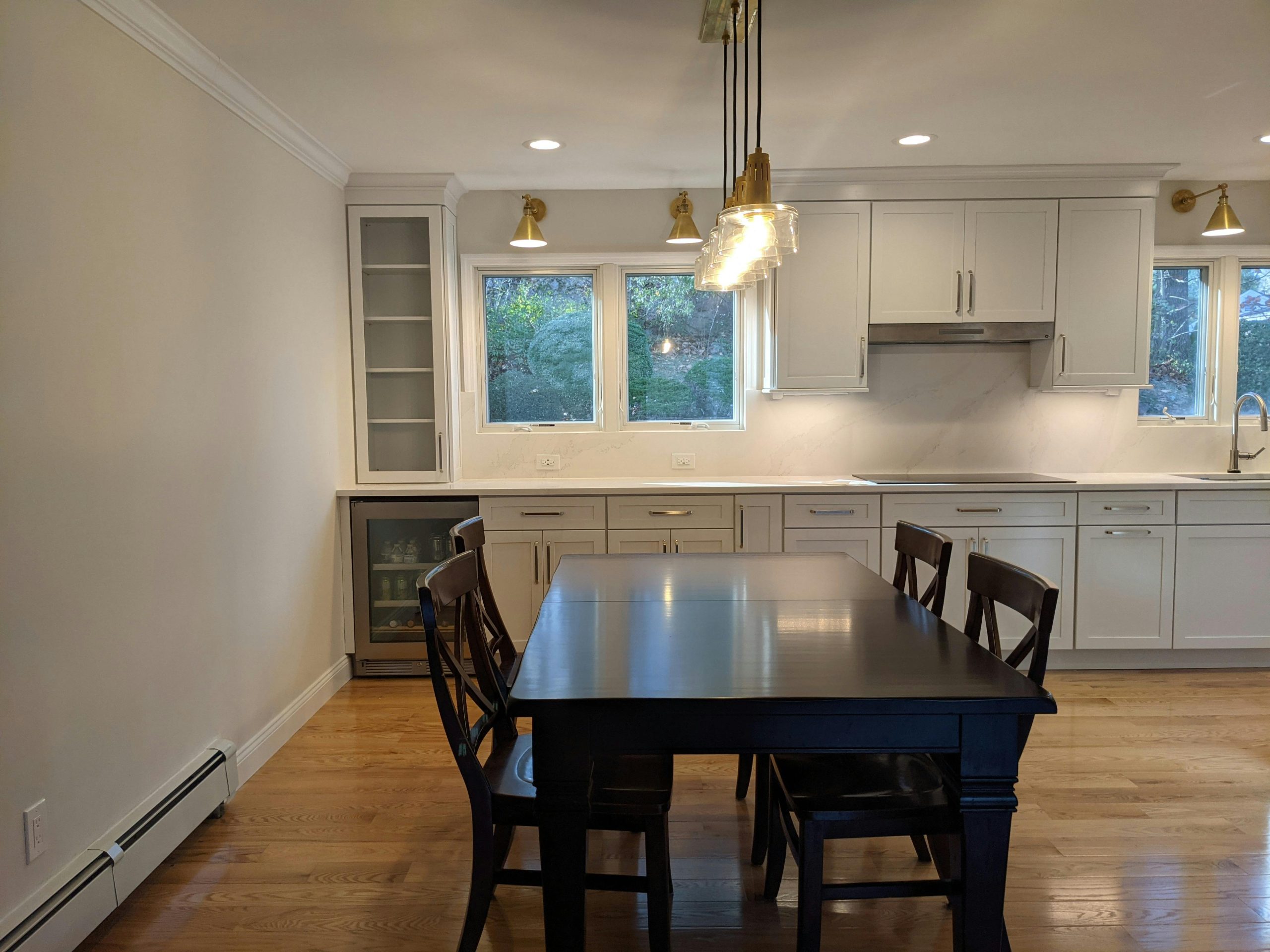 Bright modern kitchen with wooden dining table and ample natural light from large windows.