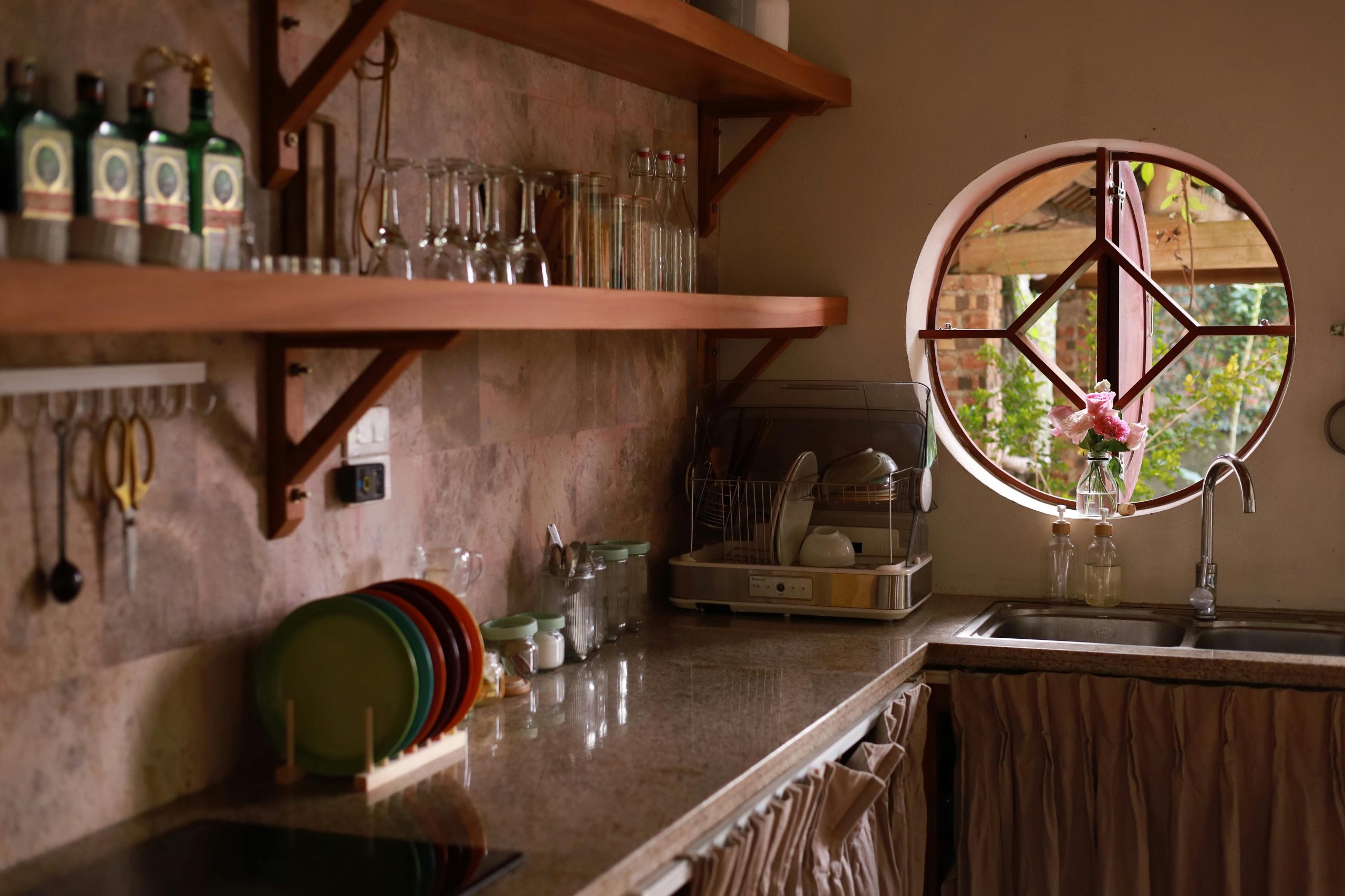 Charming rustic kitchen with wooden shelves, window view, and natural lighting in Vietnam.