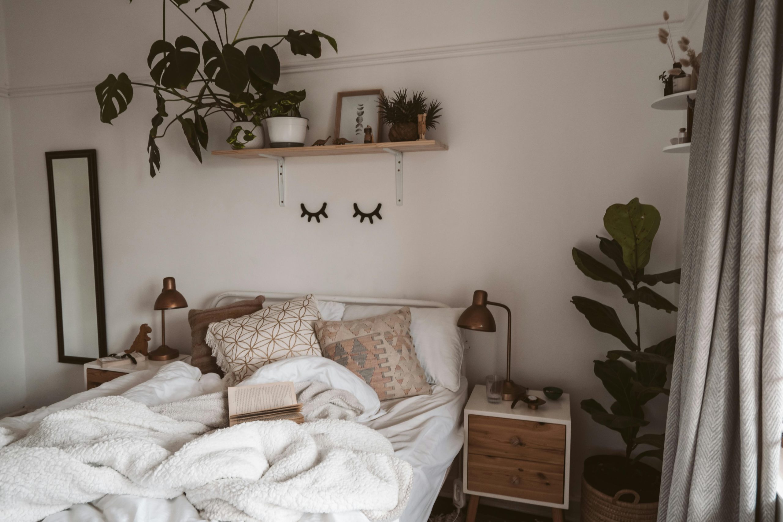 Comfortable and stylish bedroom interior featuring modern decor, greenery, and cozy textiles for a soothing atmosphere.