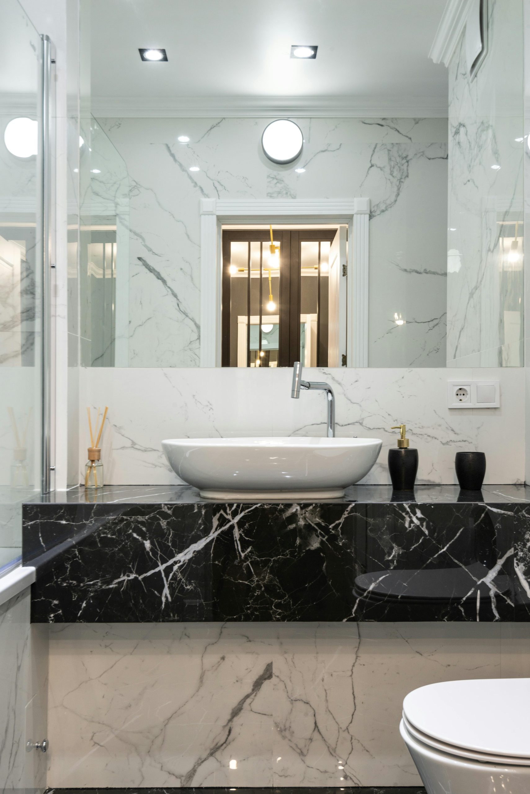 Contemporary bathroom with marble accents, featuring a minimalist sink and black countertop.