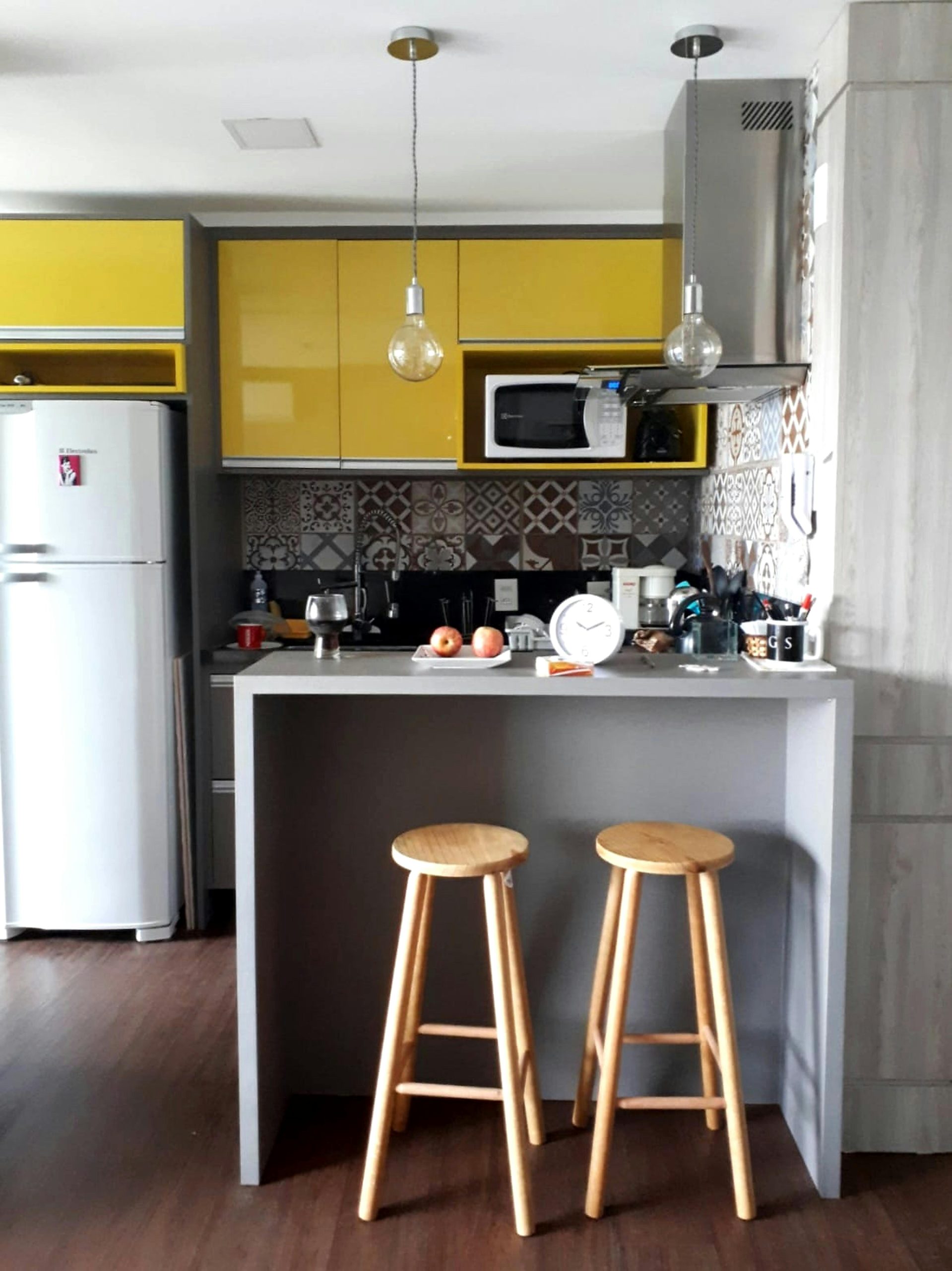 Contemporary kitchen featuring yellow cabinets, wooden stools, and stylish decor.
