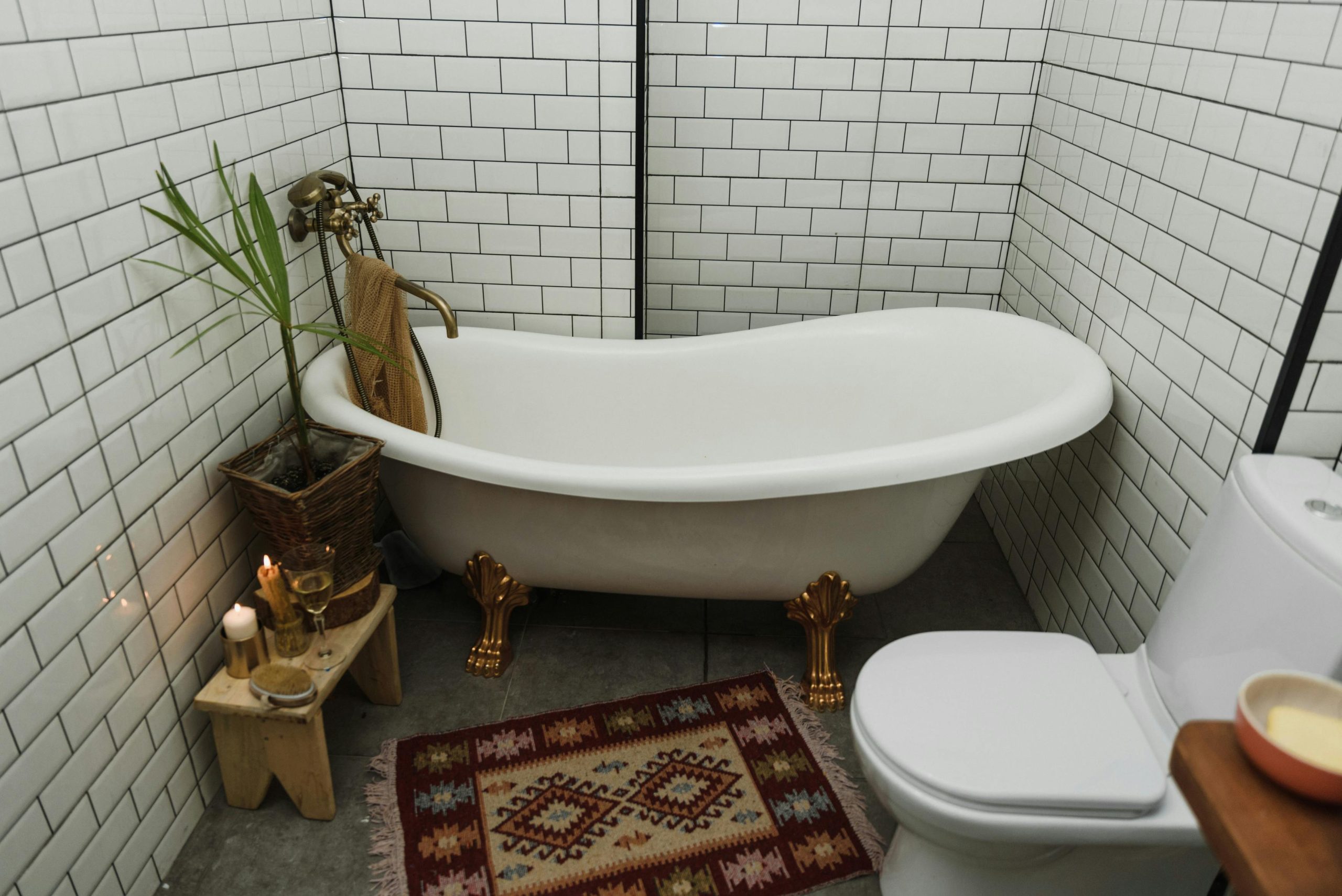 Cozy bathroom featuring a vintage-style clawfoot bathtub, white tiles, and a patterned rug for a warm interior design.