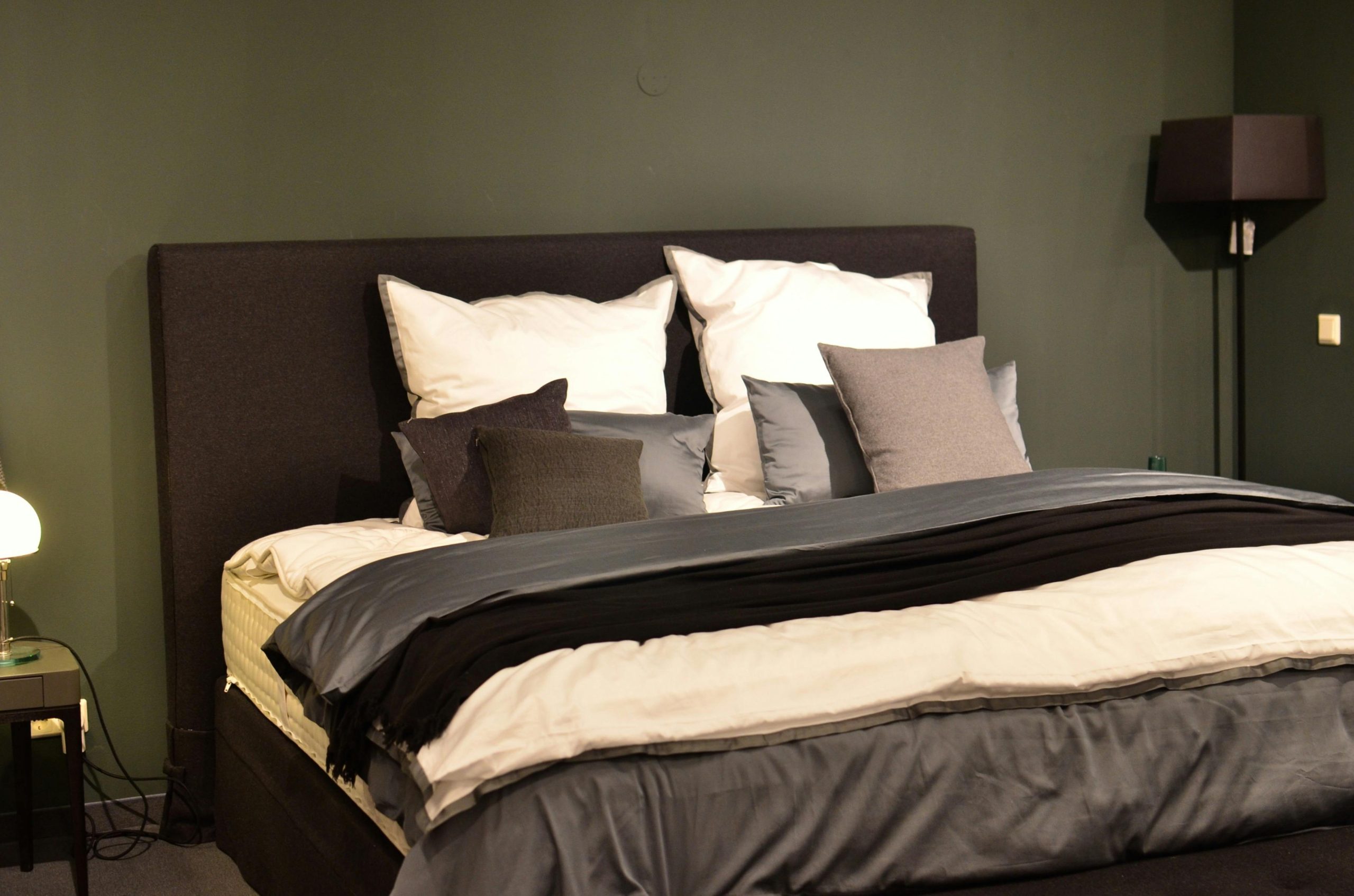 Creative design of bed with collection of cushions and cover between lamps in house
