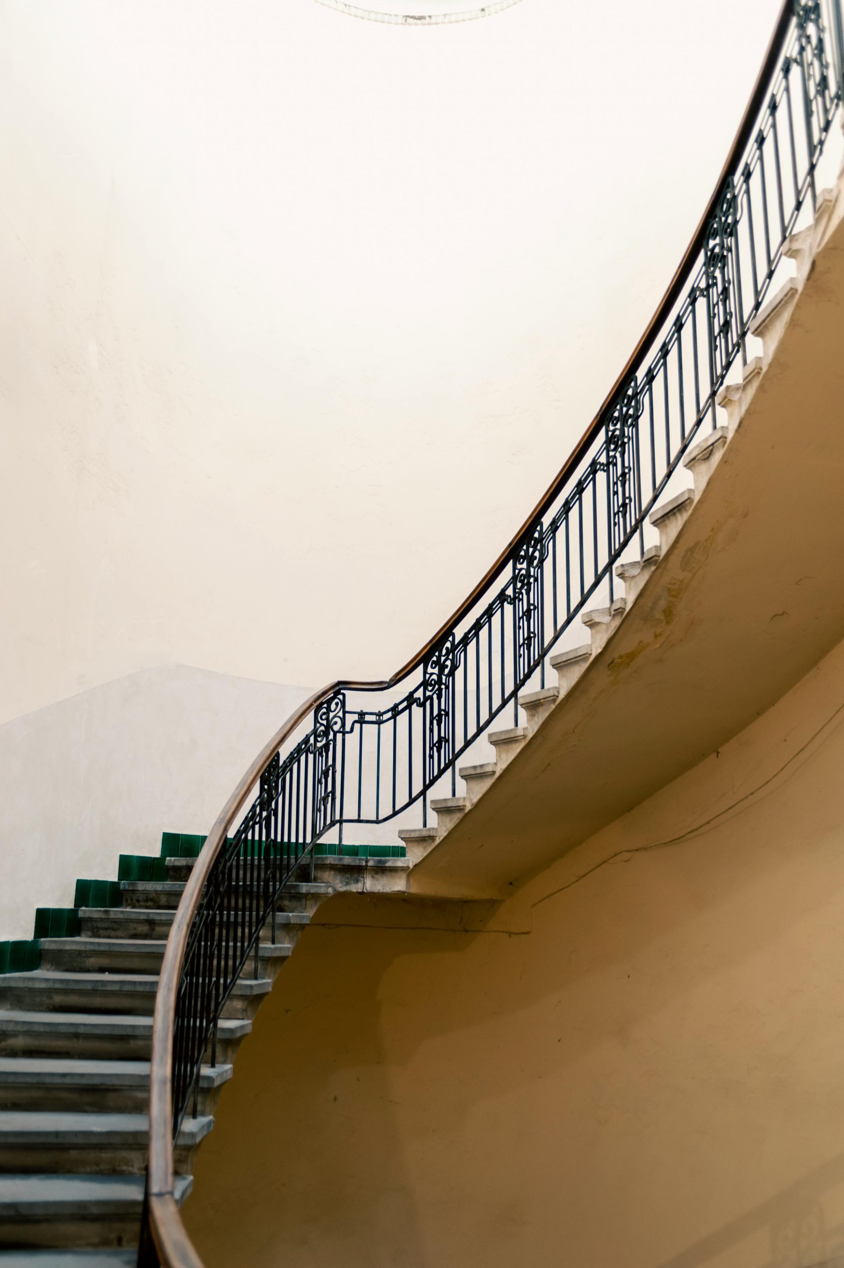 Curved staircase with wrought iron railing in historic Lviv interior, showcasing architectural elegance.