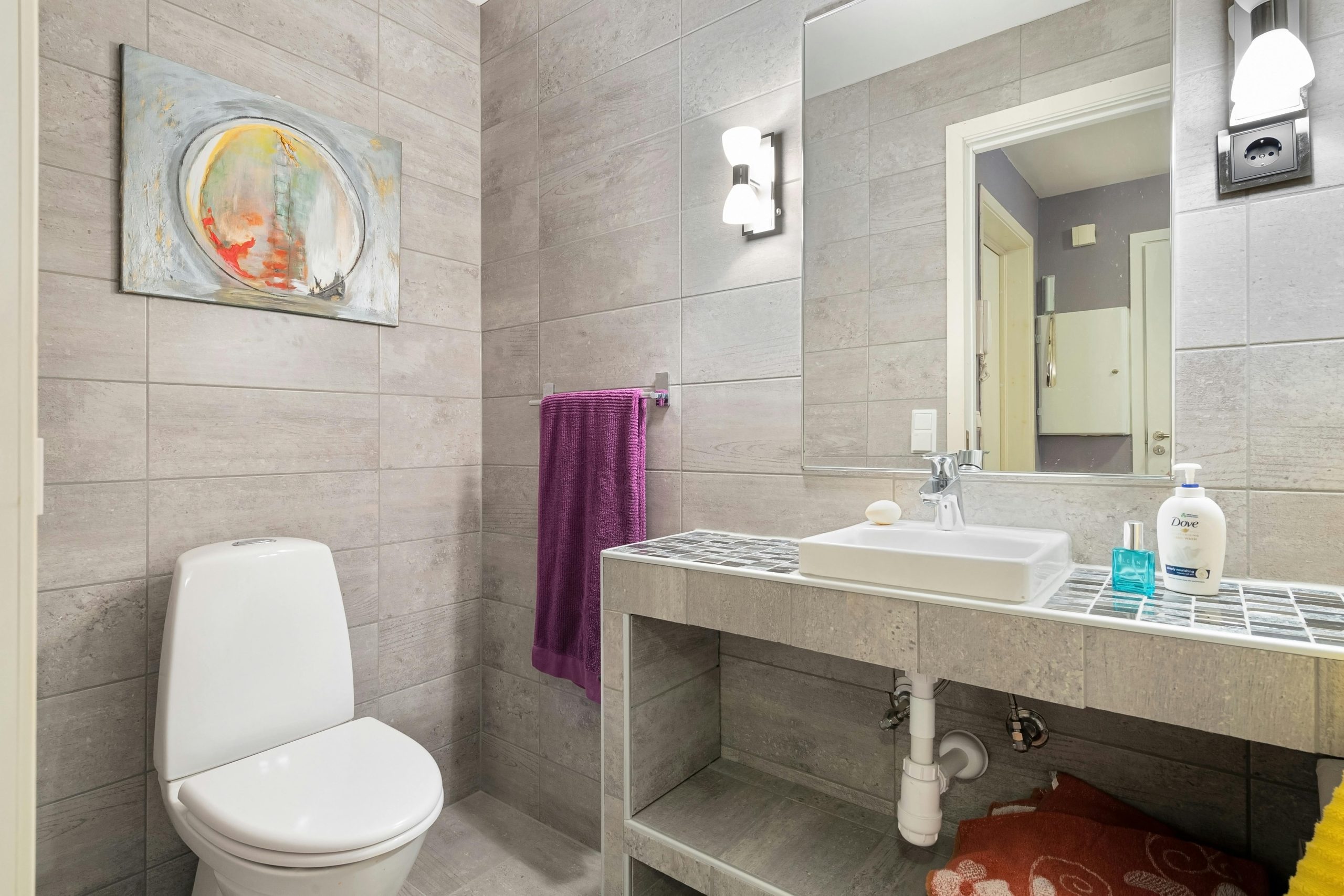 Elegant bathroom featuring contemporary design with clean lines, a toilet, sink, and artistic wall decor.