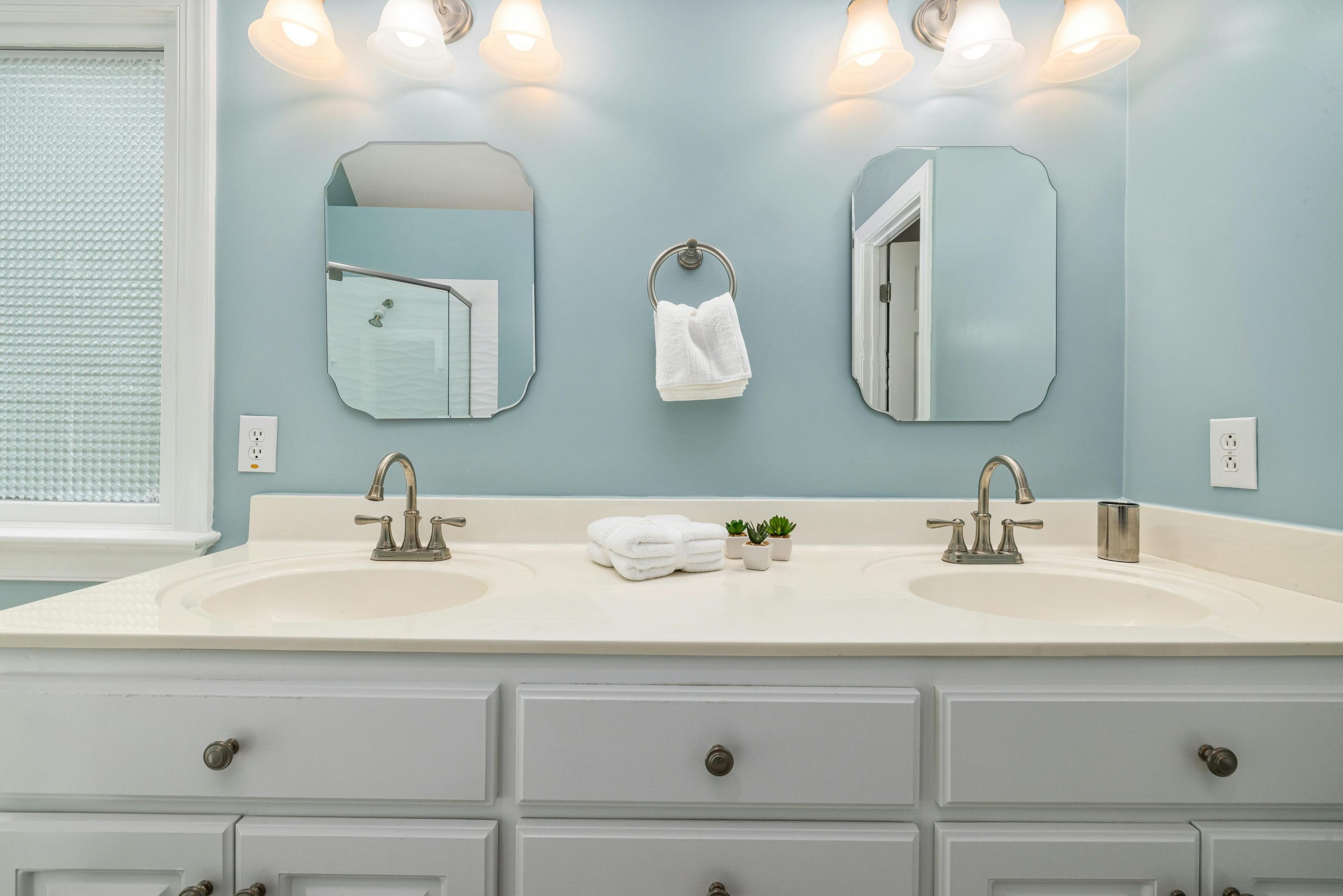 Elegant bathroom vanity setup featuring dual sinks, mirrors, and soft lighting.