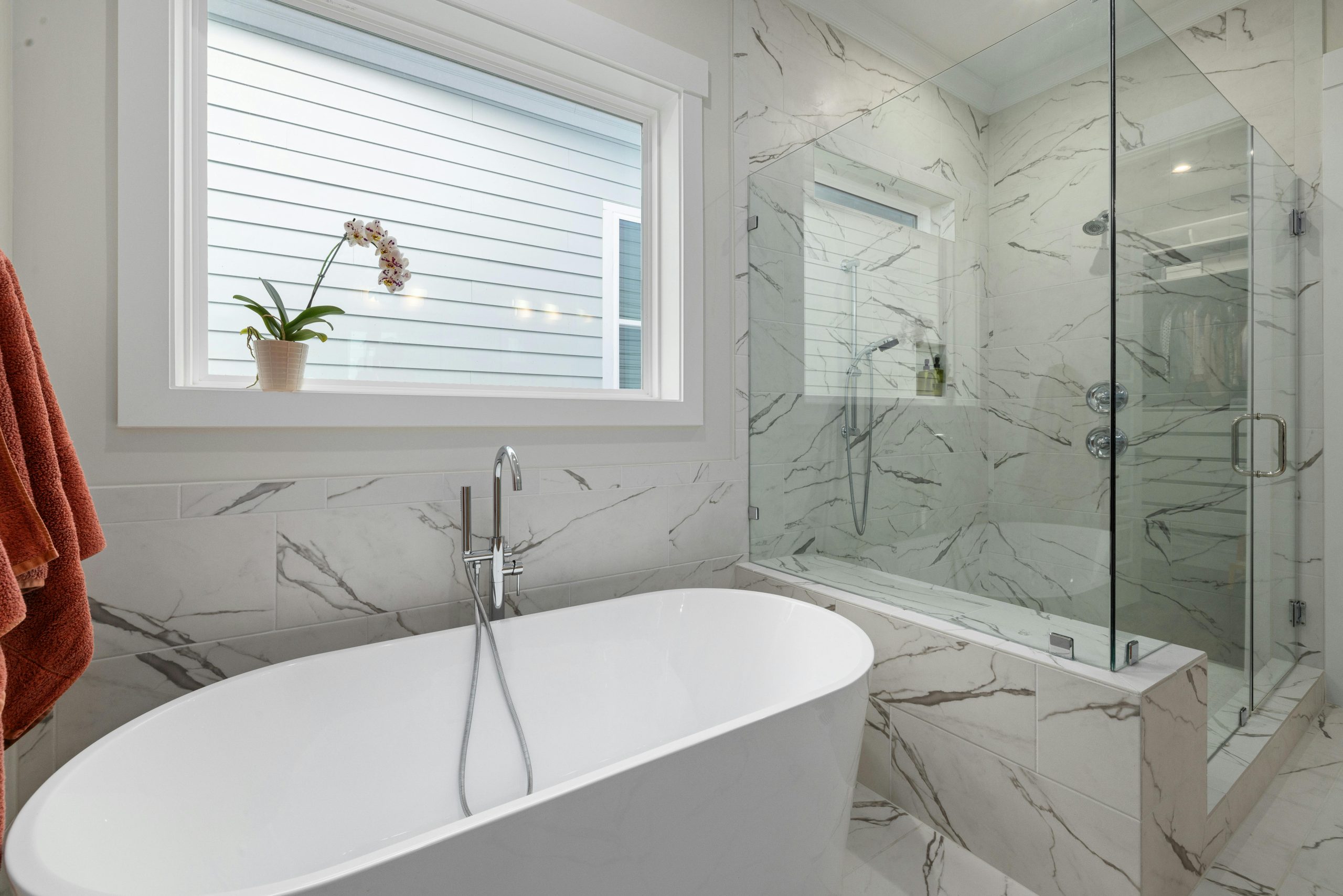 Elegant bathroom with marble tiles, a glass shower, and freestanding tub.