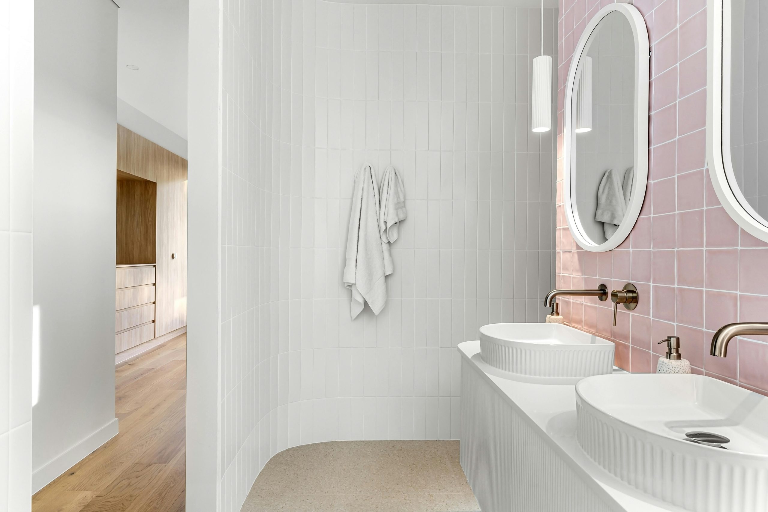 Elegant minimalist bathroom featuring pink tiles and dual sinks with modern fixtures.