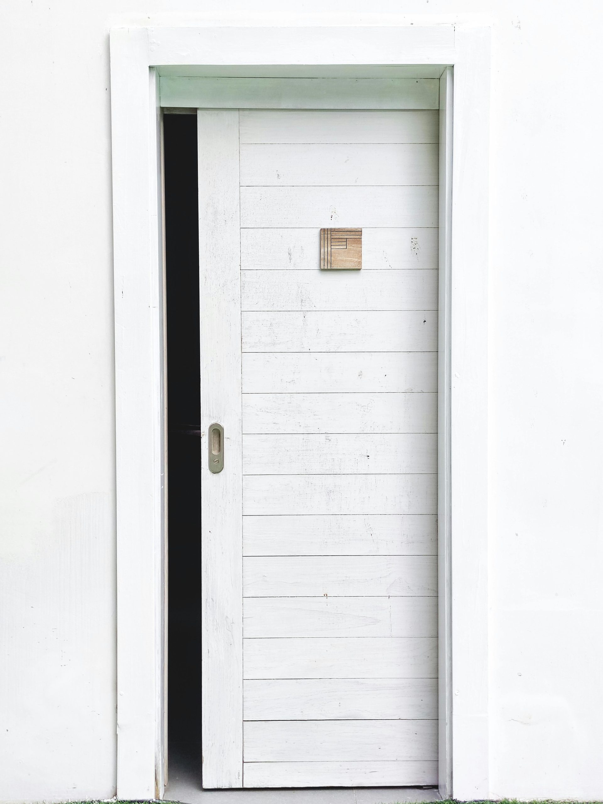 Elegant minimalist design featuring a white sliding door slightly open on a white wall, perfect for modern architecture concepts.