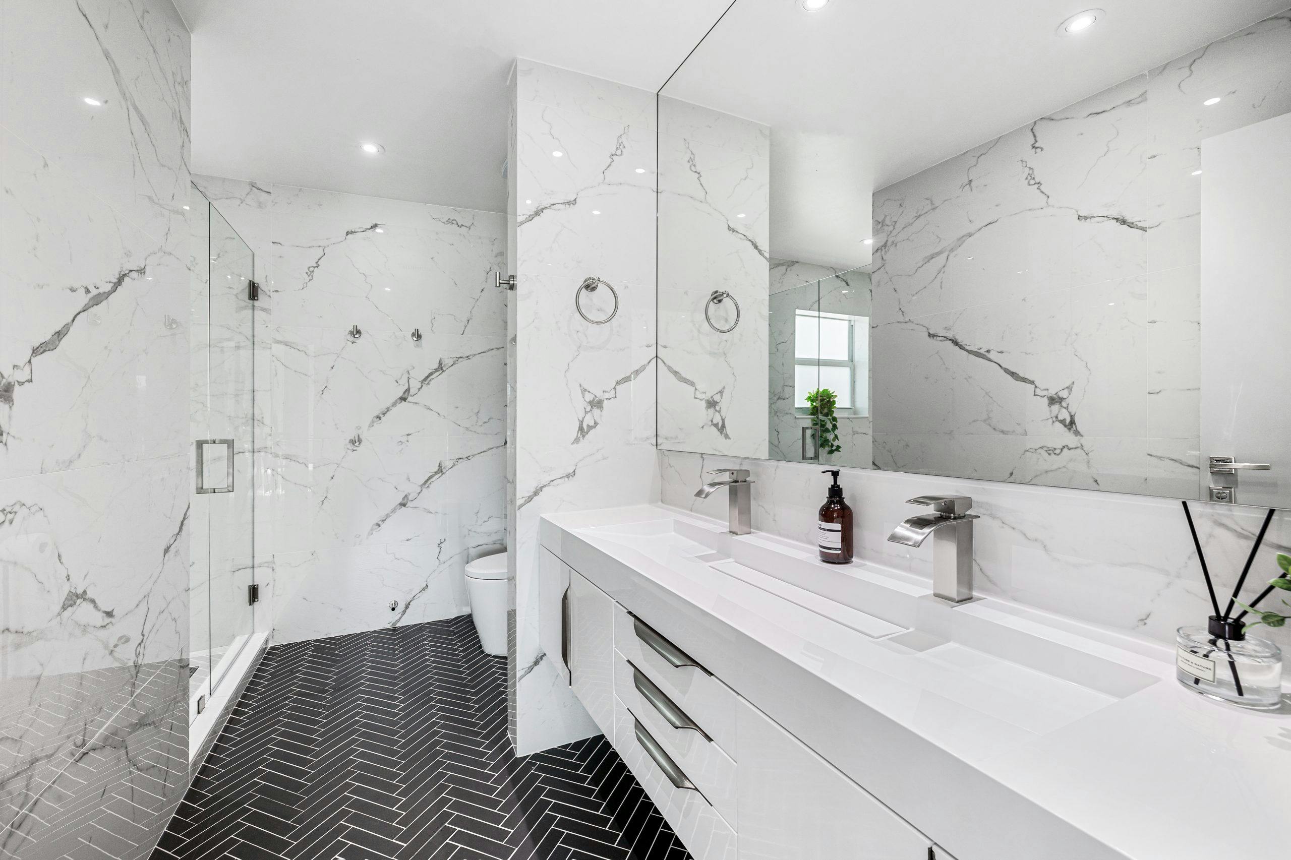 Explore the elegance of a modern bathroom featuring marble walls and sleek fixtures.