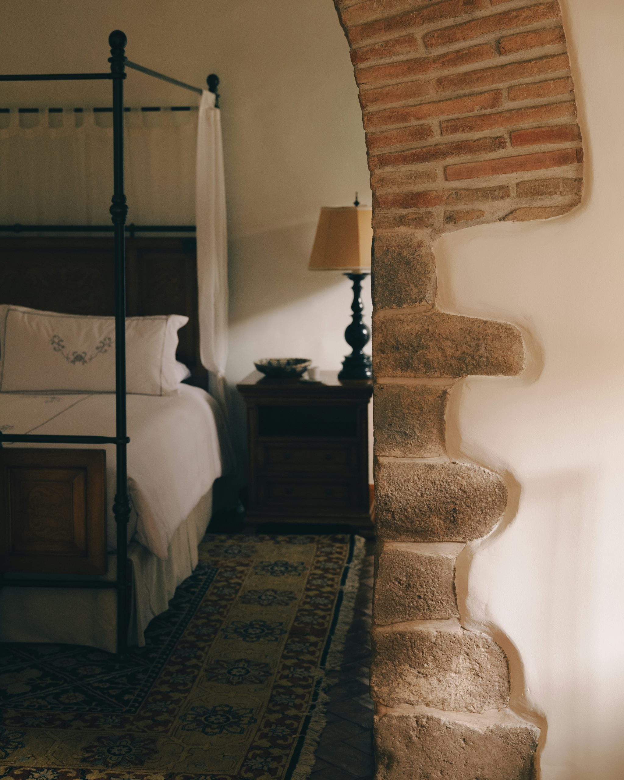 Four-poster bed with bedside table and lamp.