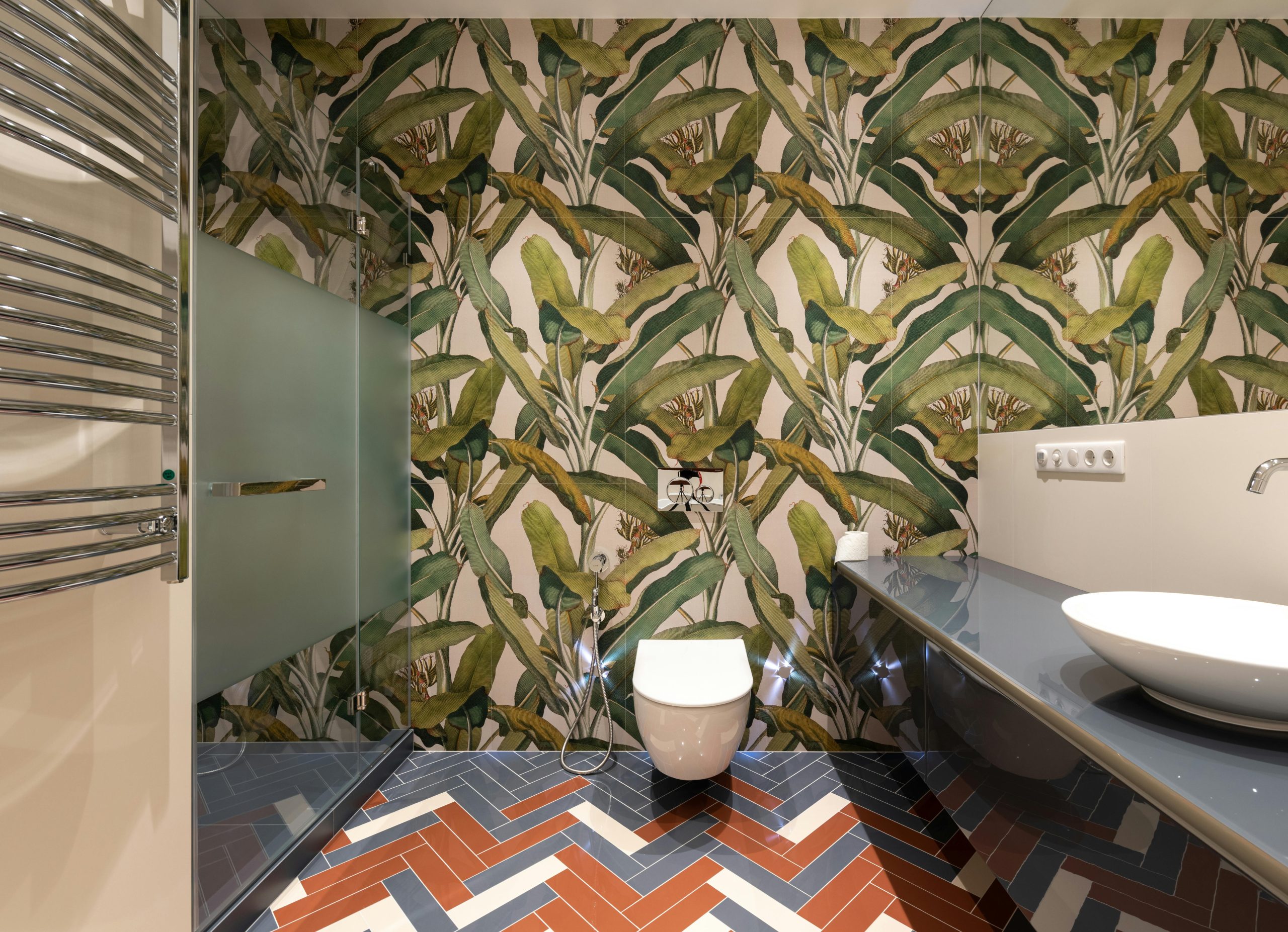 Interior of contemporary bathroom with shower cabin and ceramic sink and toilet bowl decorated with creative wallpapers with green plants paintings