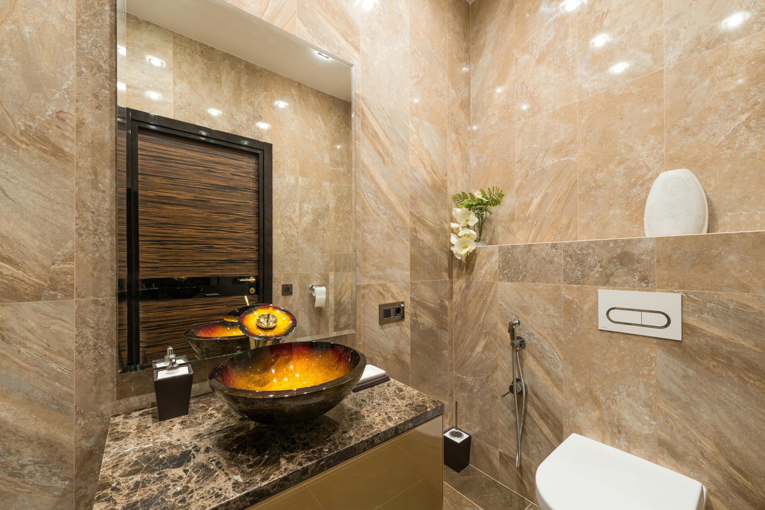 Interior of contemporary bathroom with stylish sink under mirror and tilled walls in luxury apartment