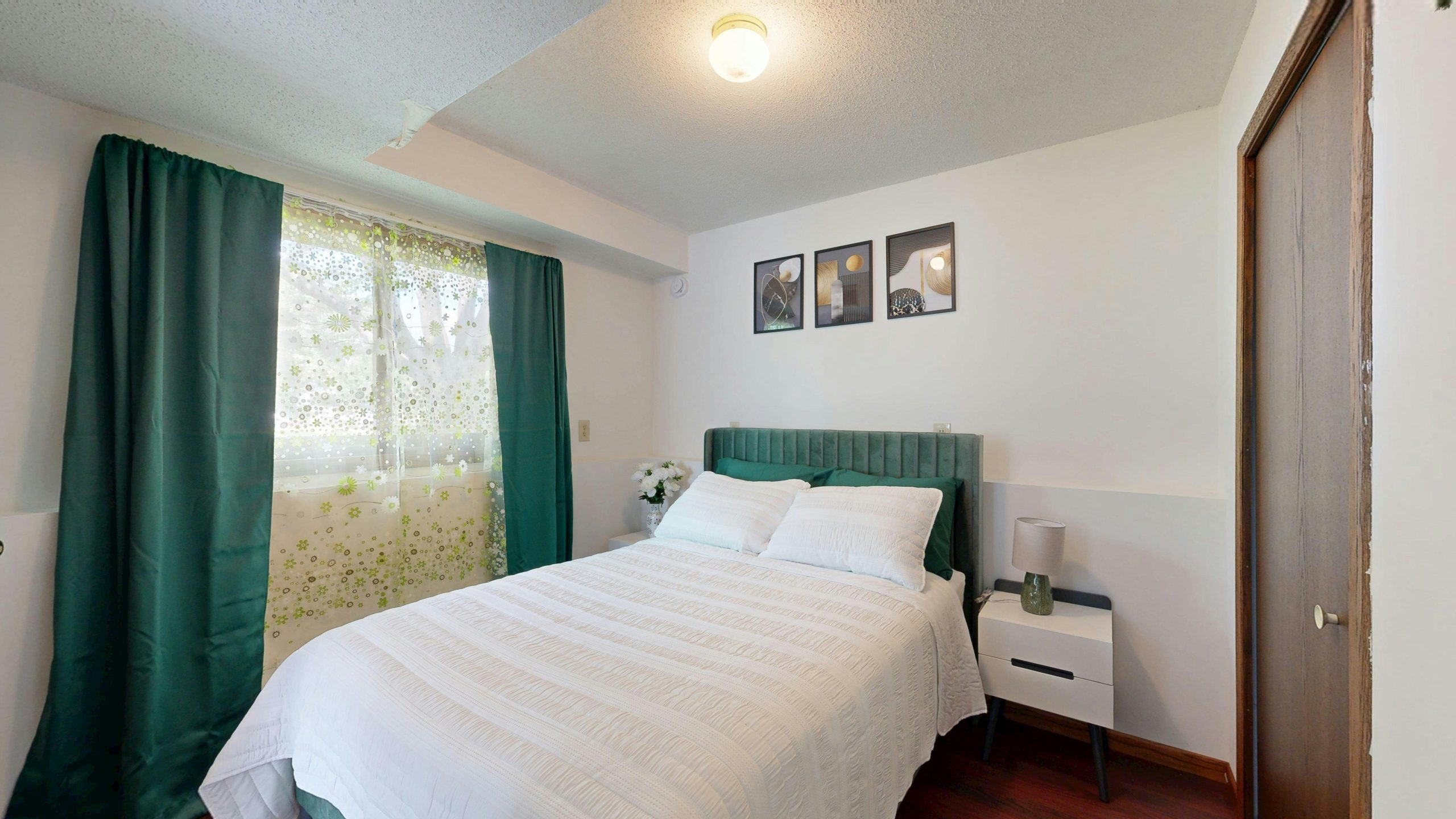 Inviting bedroom with green decor elements, natural lighting, and modern art.