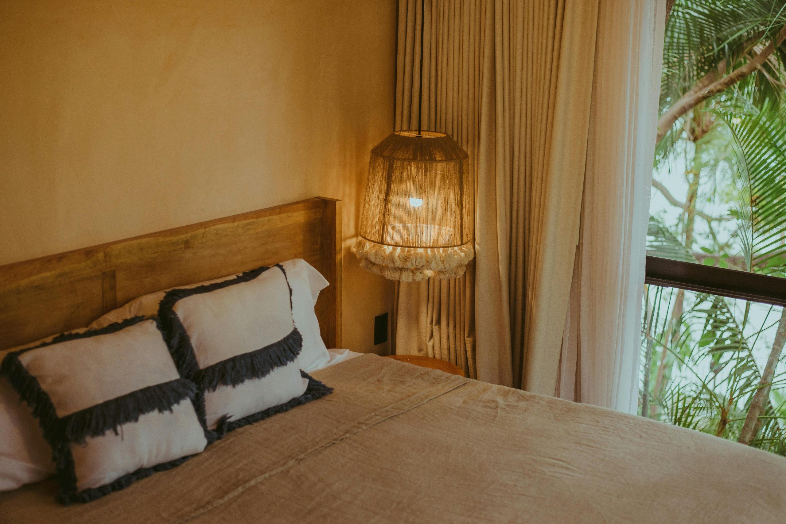 Inviting resort bedroom with warm lighting and a view of palm trees through the window.