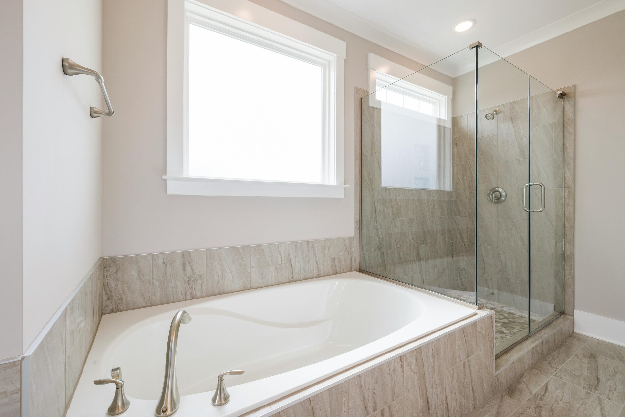Luxurious bathroom interior featuring a white bathtub and glass-enclosed shower with marble accents.