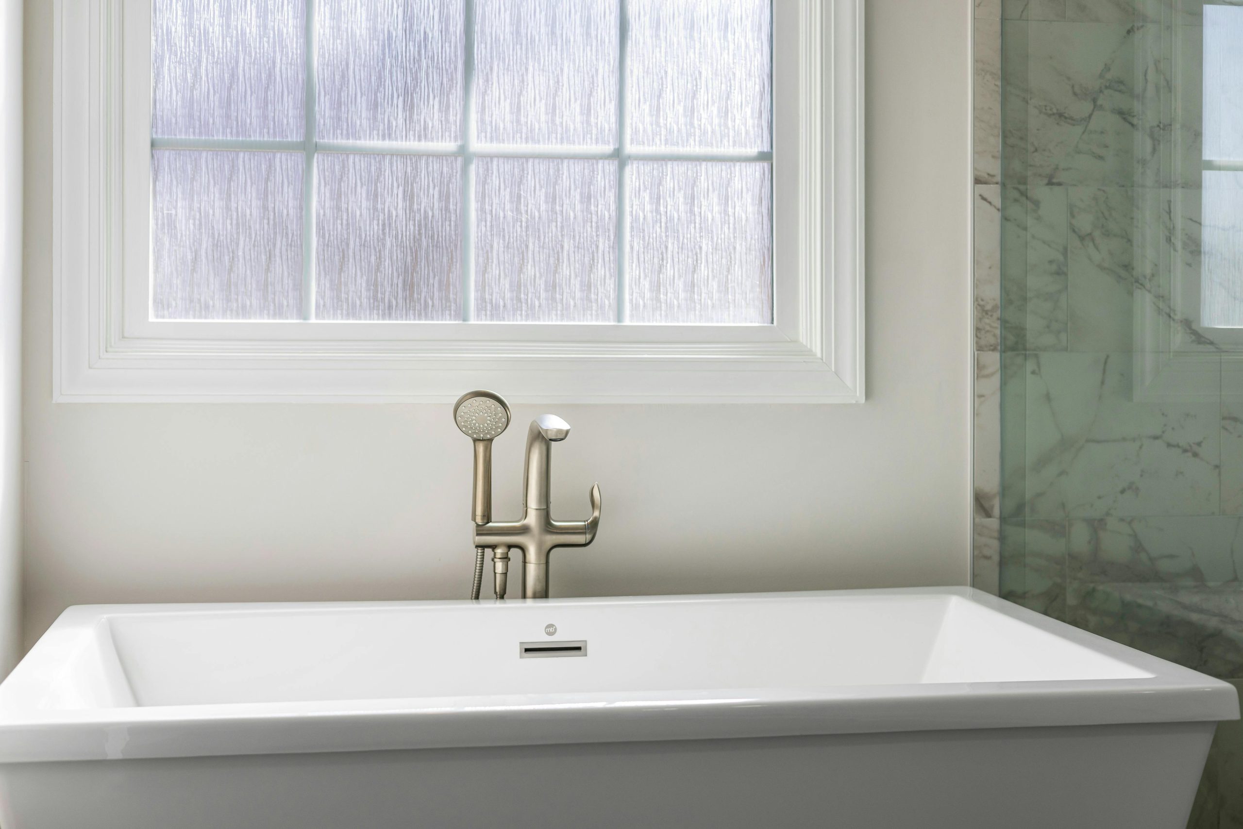 Luxurious bathroom interior featuring a modern white bathtub and a scenic window with natural light.