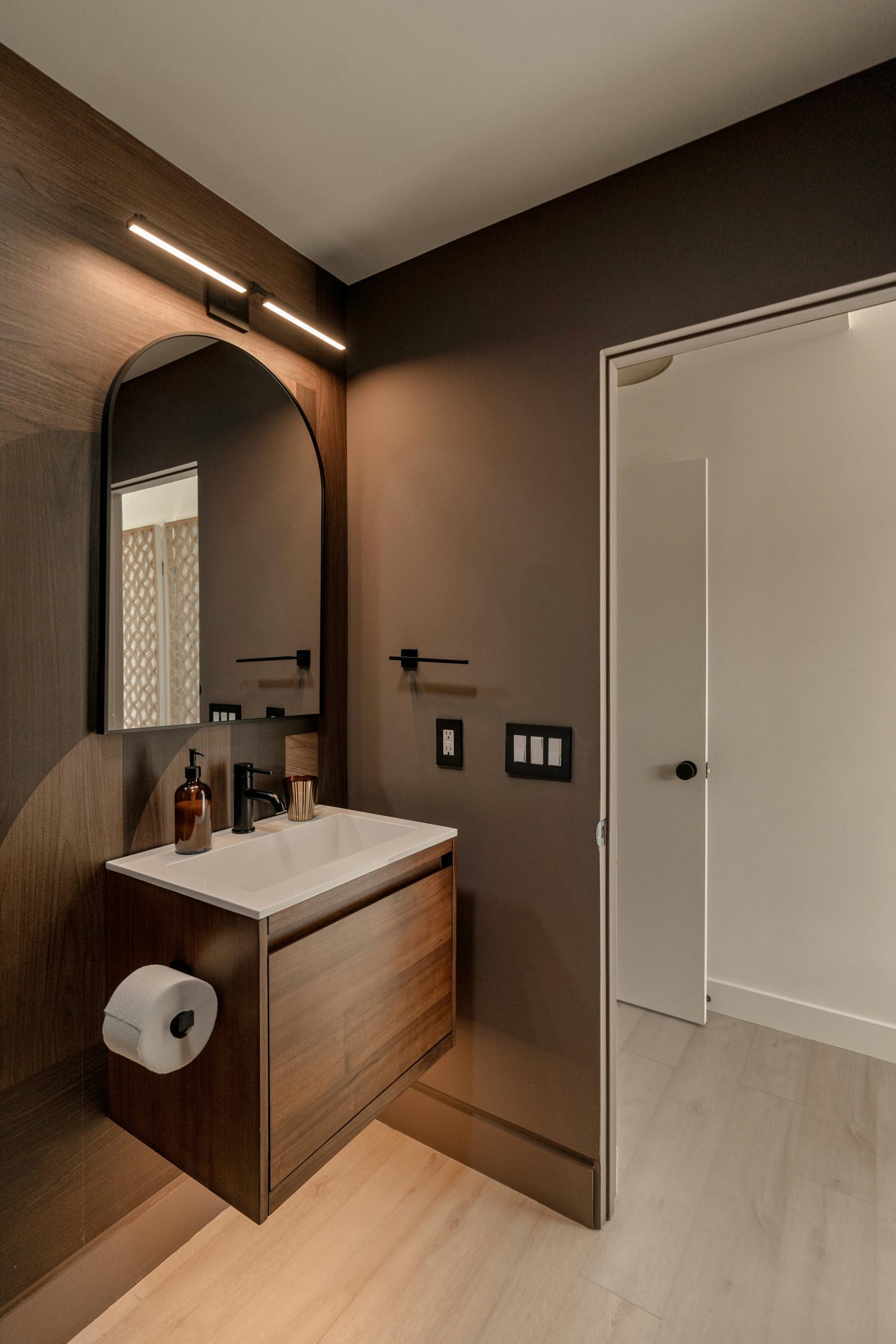 Luxury bathroom renovation with a stone vanity, floating cabinets, and walk-in shower. Soft ambient lighting and modern design create a high-end, minimalist aesthetic.
