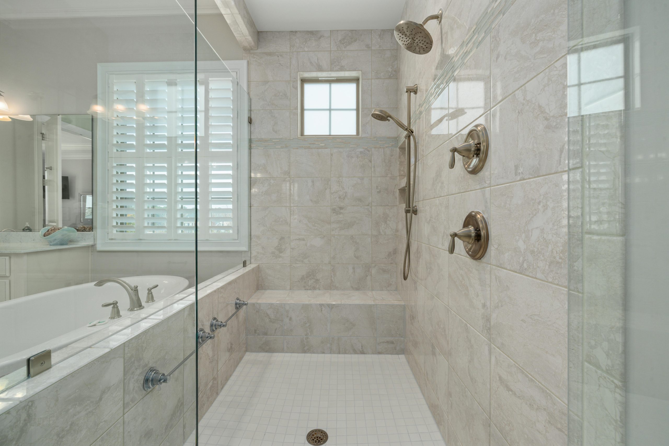 Modern bathroom interior showcasing a luxurious shower with white tiles and glass doors.