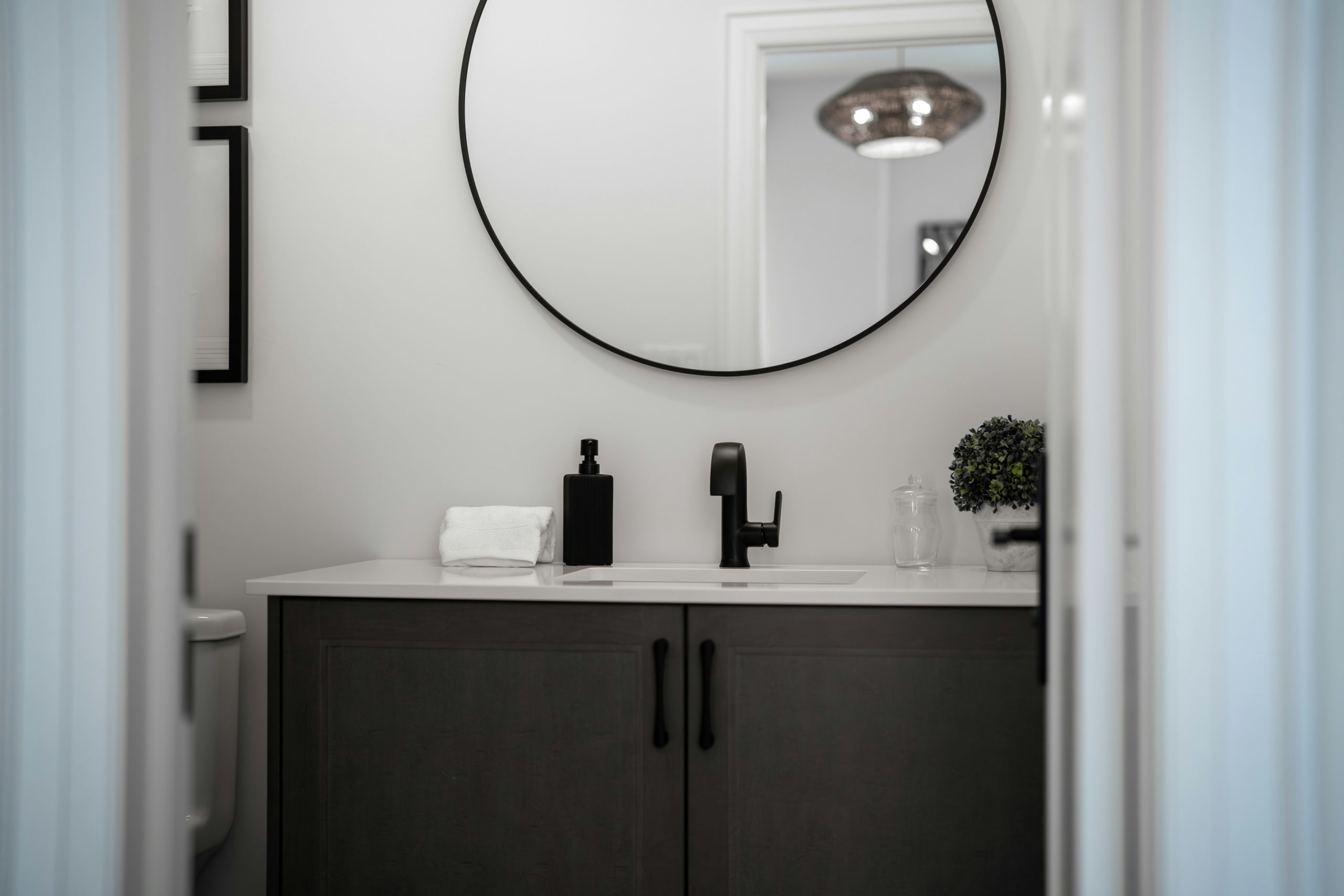 Modern bathroom vanity with a round mirror above.