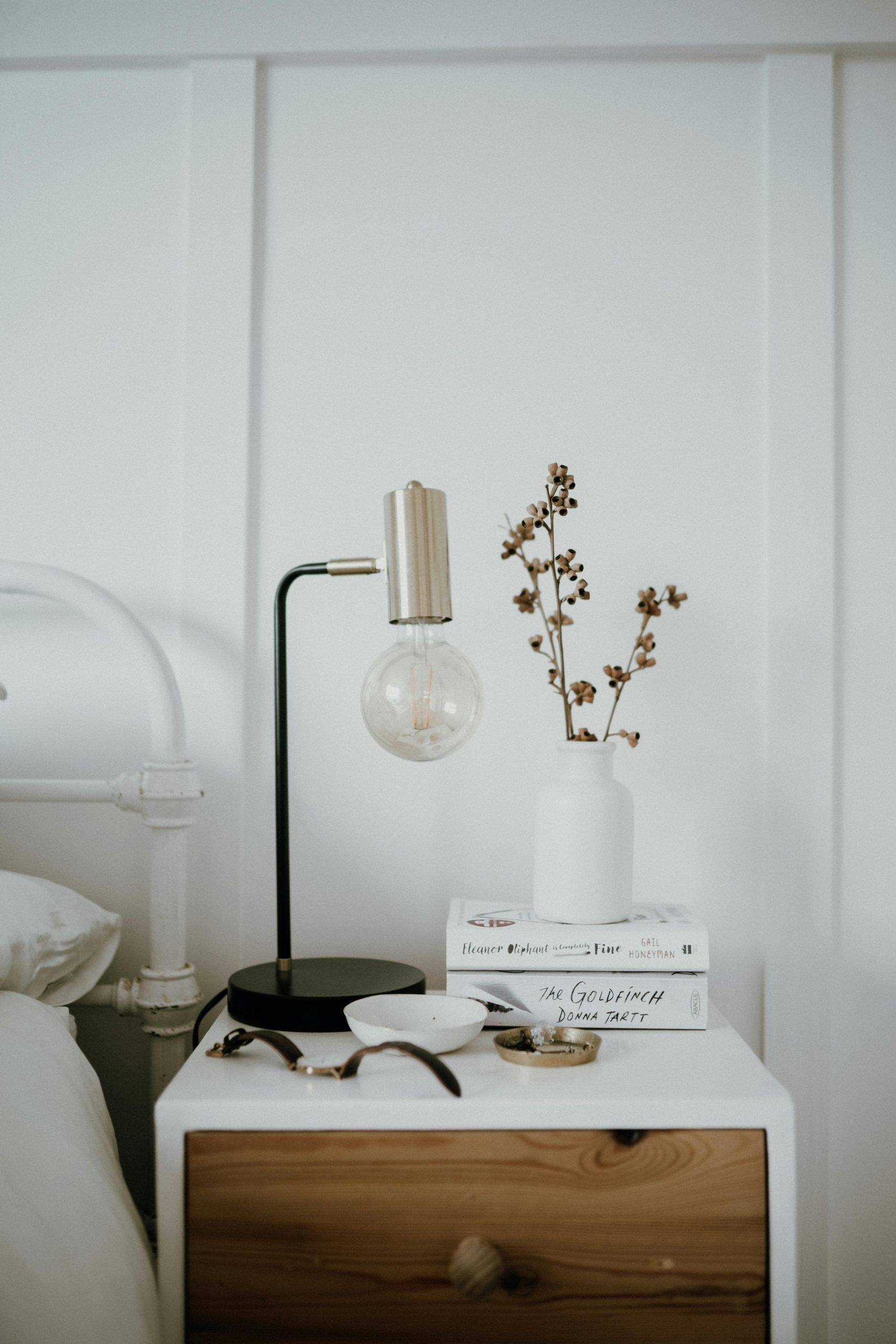 Modern bedroom setup featuring a stylish table lamp and decorative ceramic vase.