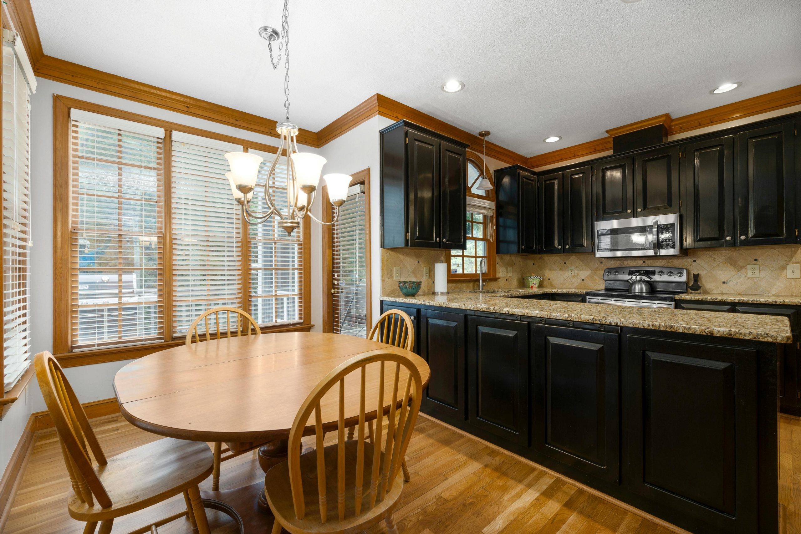 Modern kitchen and dining area featuring black cabinets and wooden furniture.