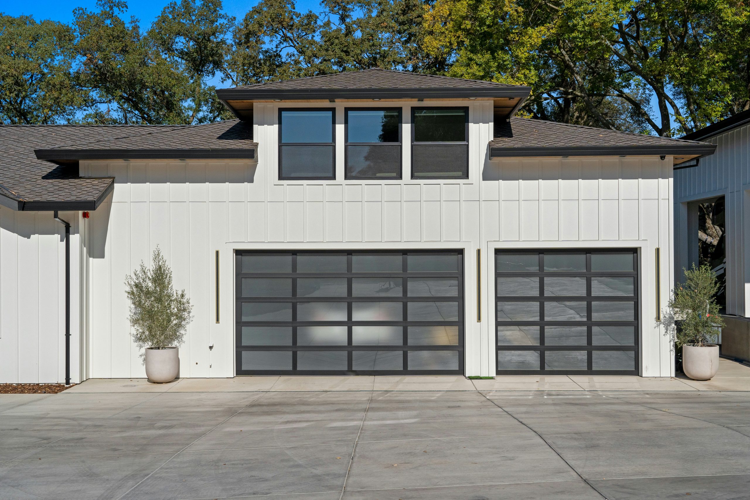 Modern residential home exterior featuring a clean white facade, minimalist architecture, and contemporary garage doors in natural daylight.