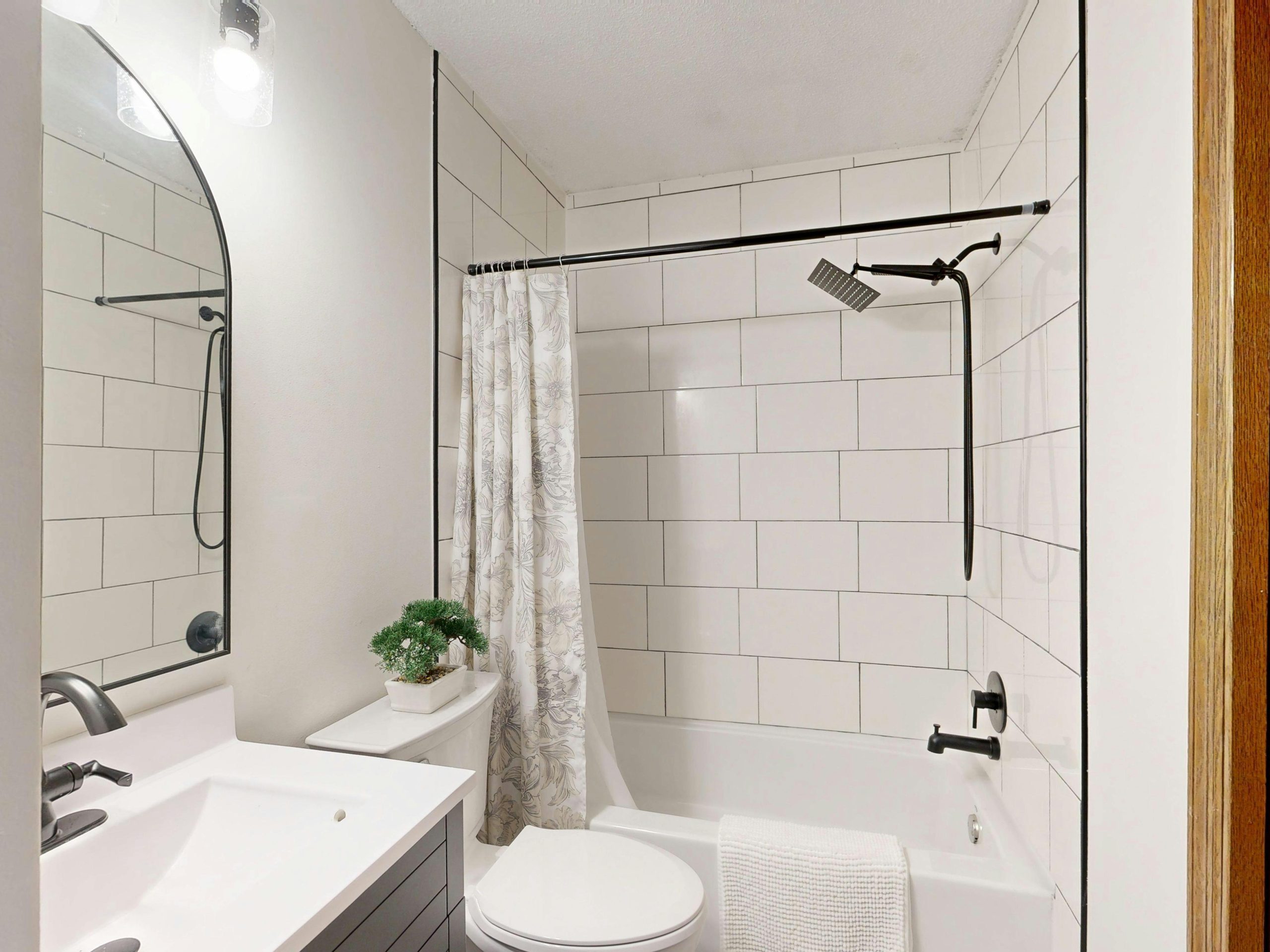 Sleek and clean modern bathroom with white tiles and black fixtures.