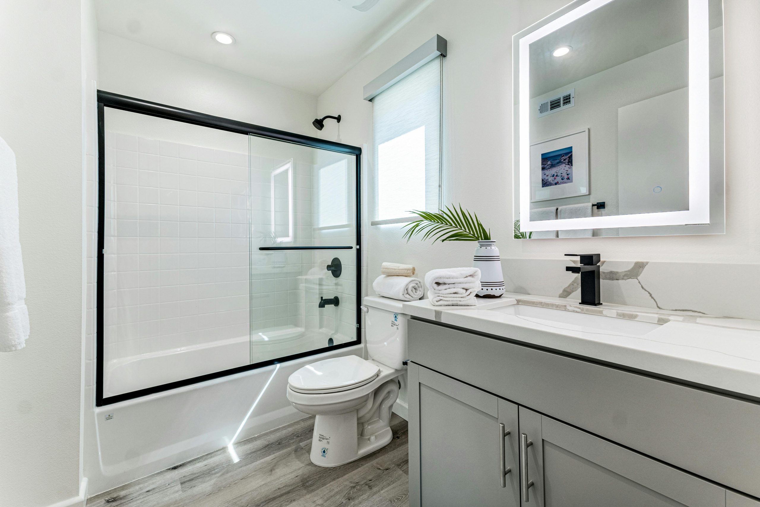 Sleek and stylish bathroom featuring a minimalist design with a shower, vanity, and mirror.