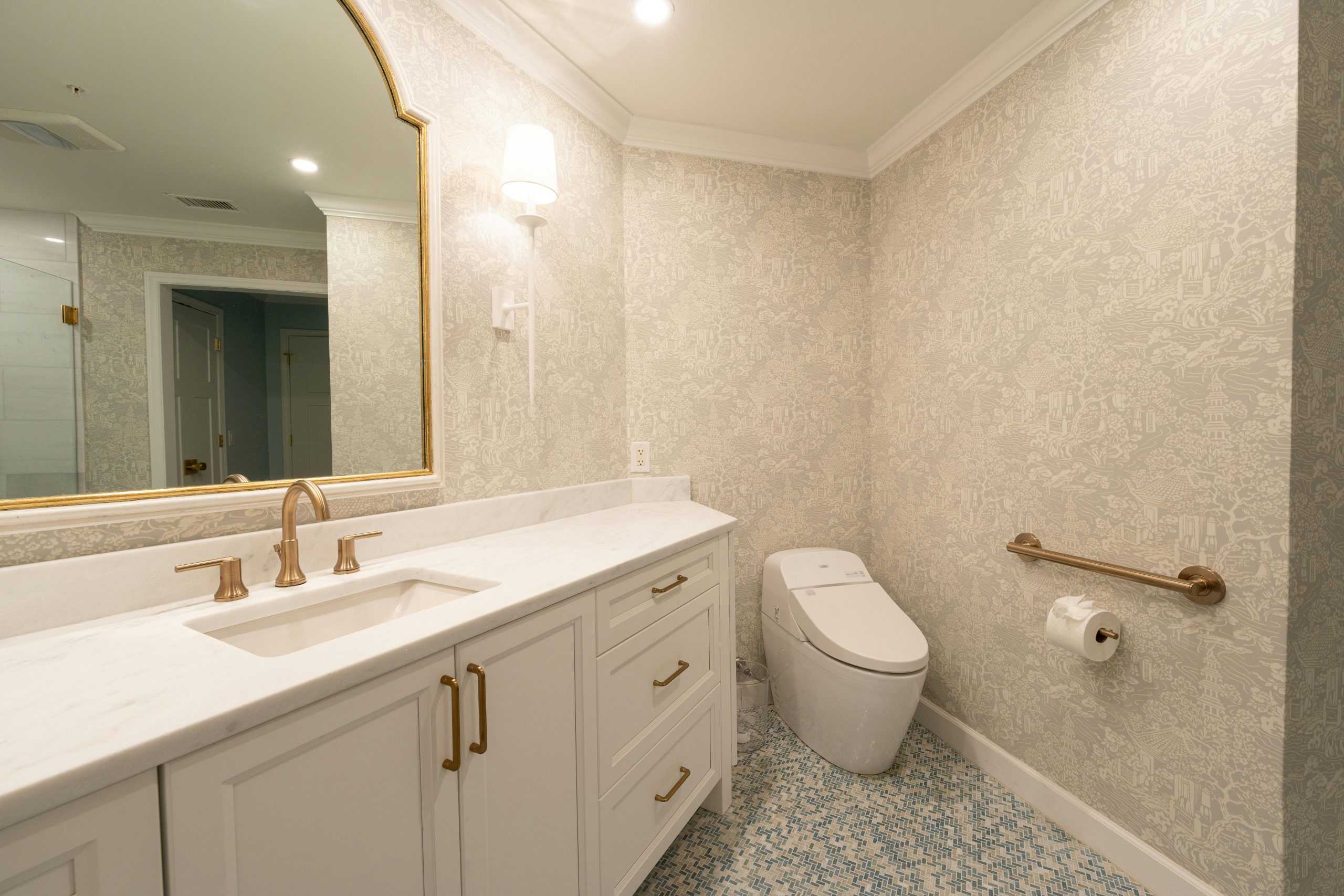 Stylish bathroom design featuring a vanity, mirror, modern toilet, and patterned wallpaper.