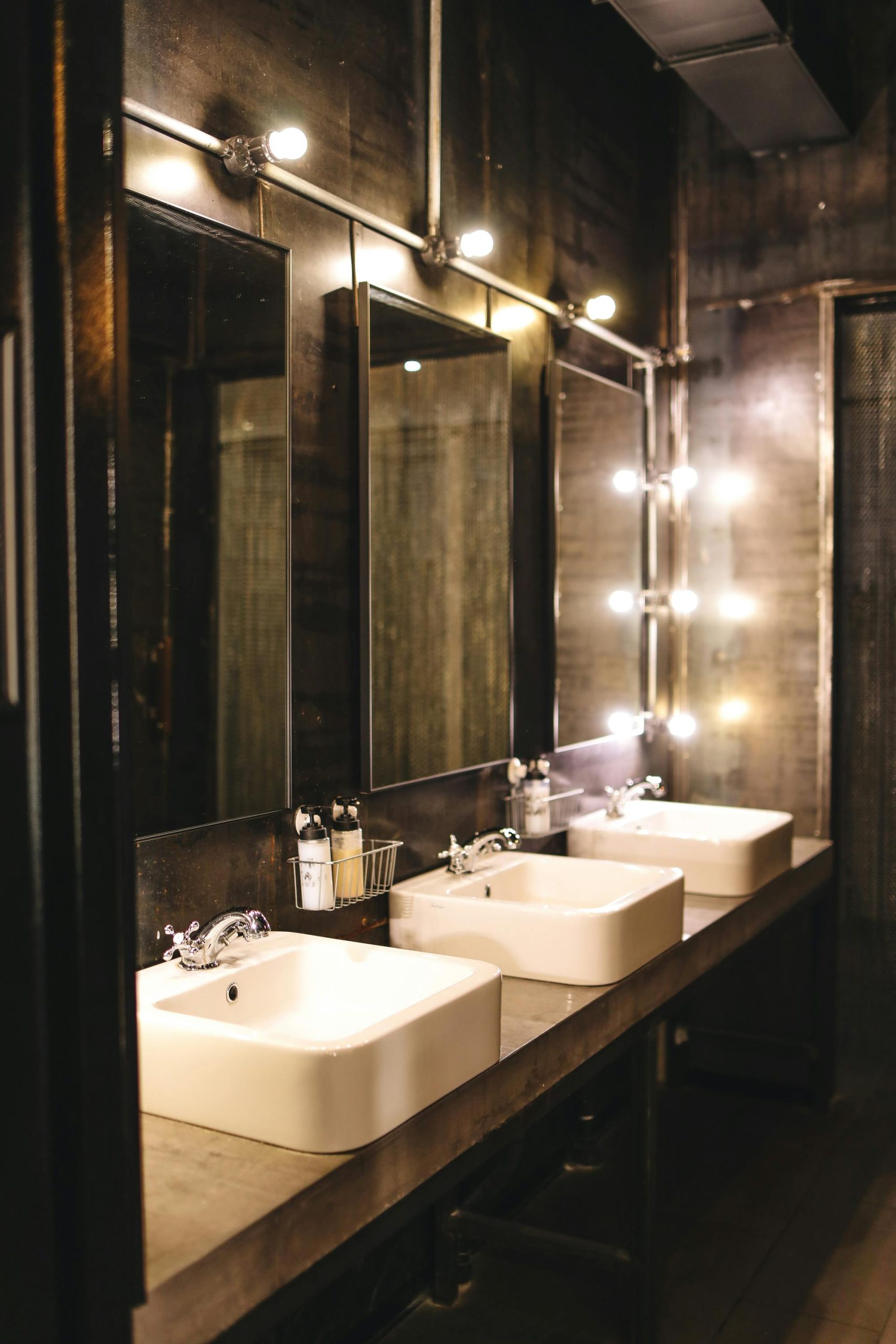 Stylish industrial bathroom interior with twin sinks and large mirrors, sleek and contemporary design.