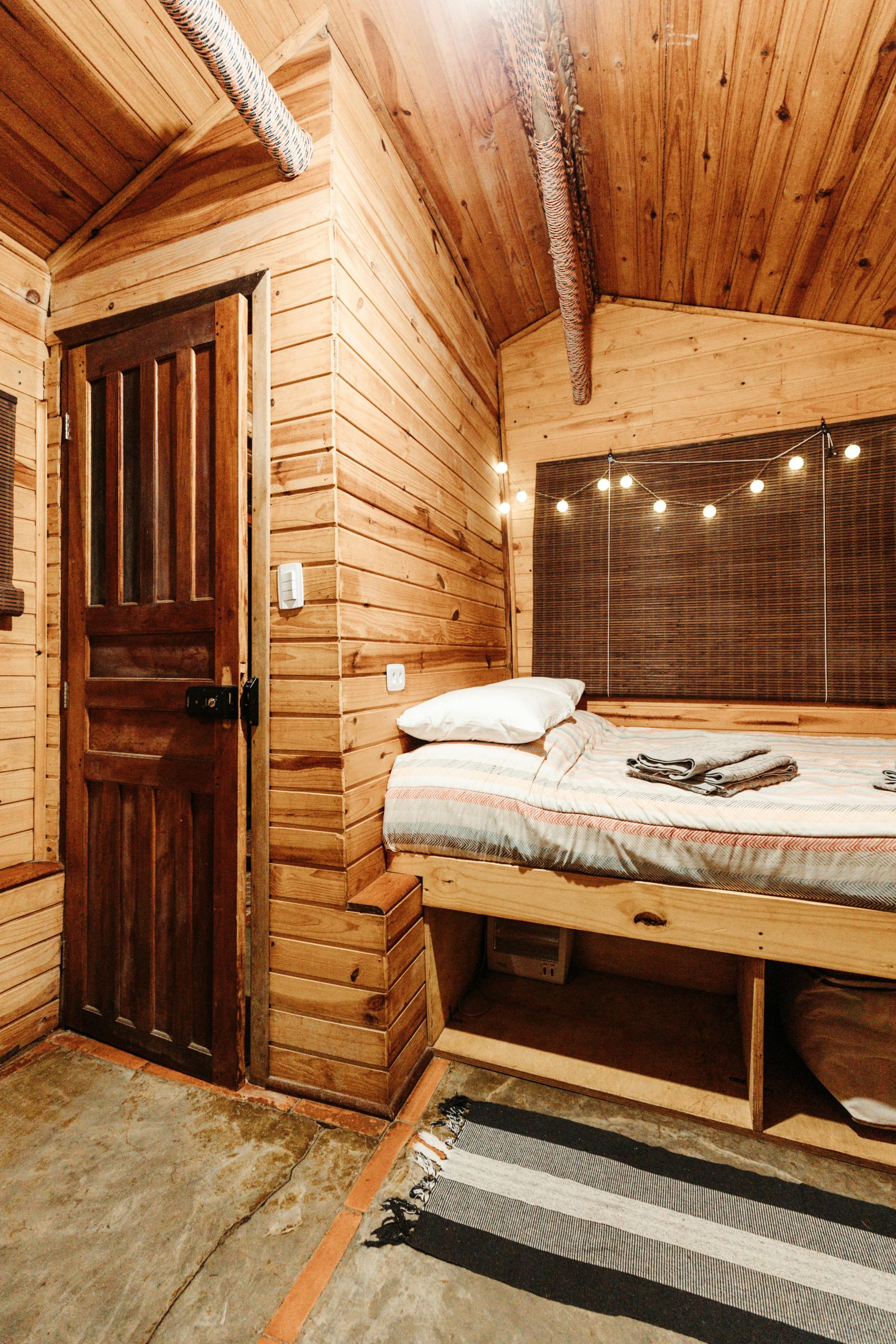 Warm and inviting cabin bedroom featuring wooden walls and string lights, perfect for a cozy retreat.