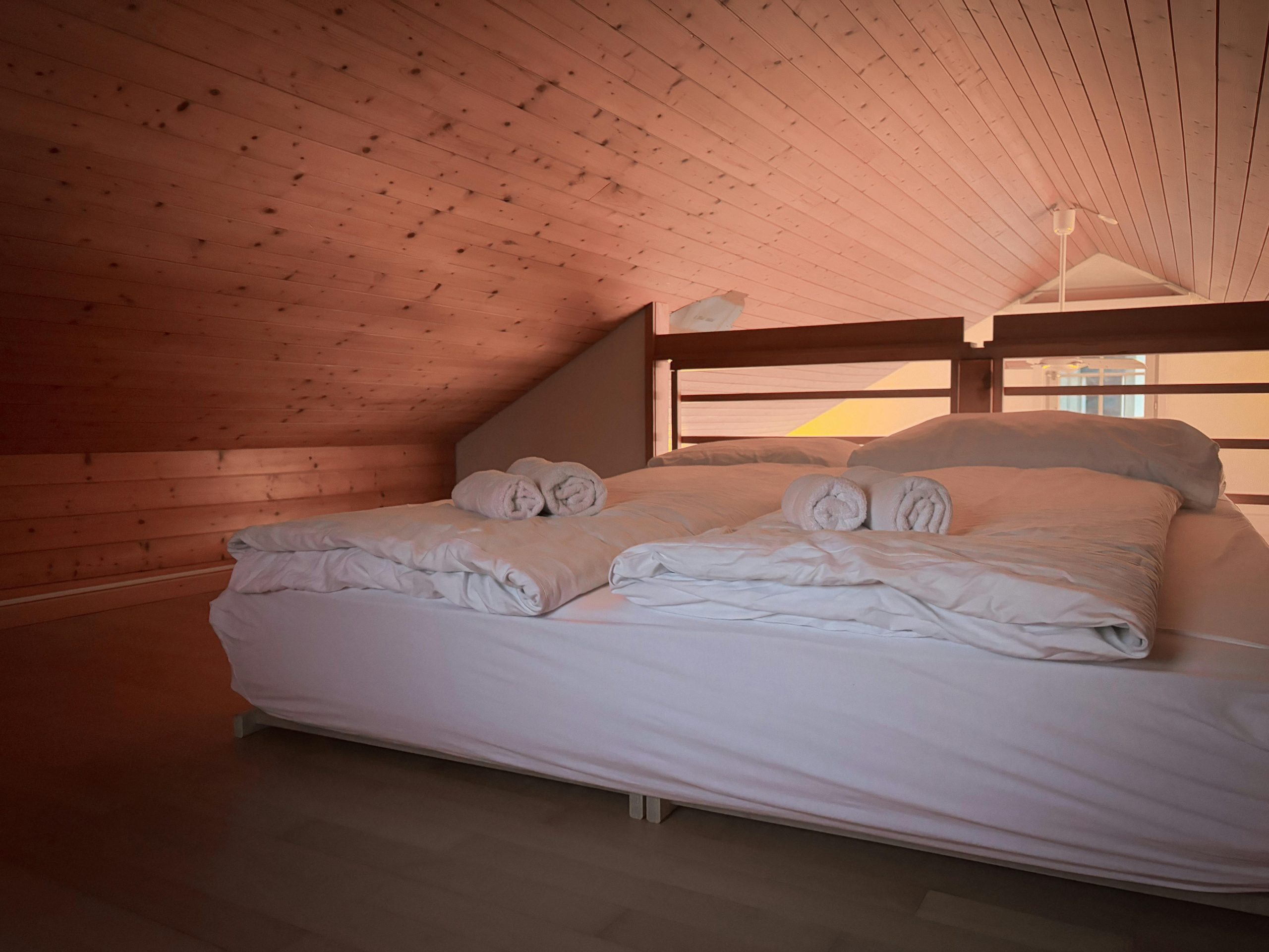 Warm, inviting loft bedroom featuring wooden ceiling and fresh linens.