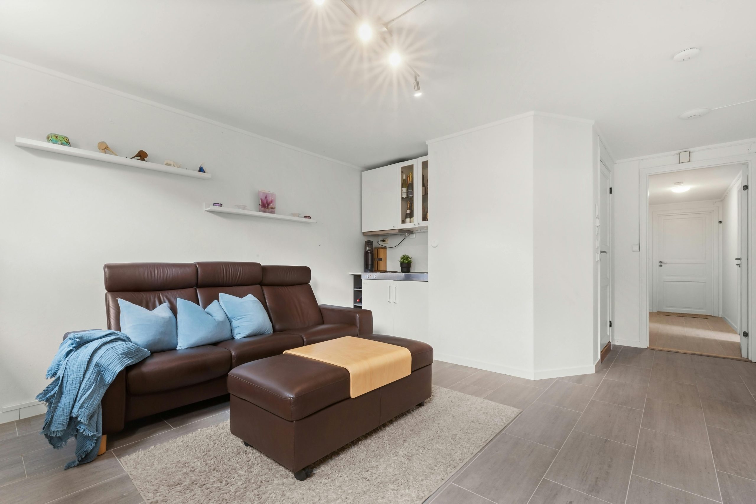 Wide-angle view of a modern living room with a brown leather sofa and sleek furnishings.