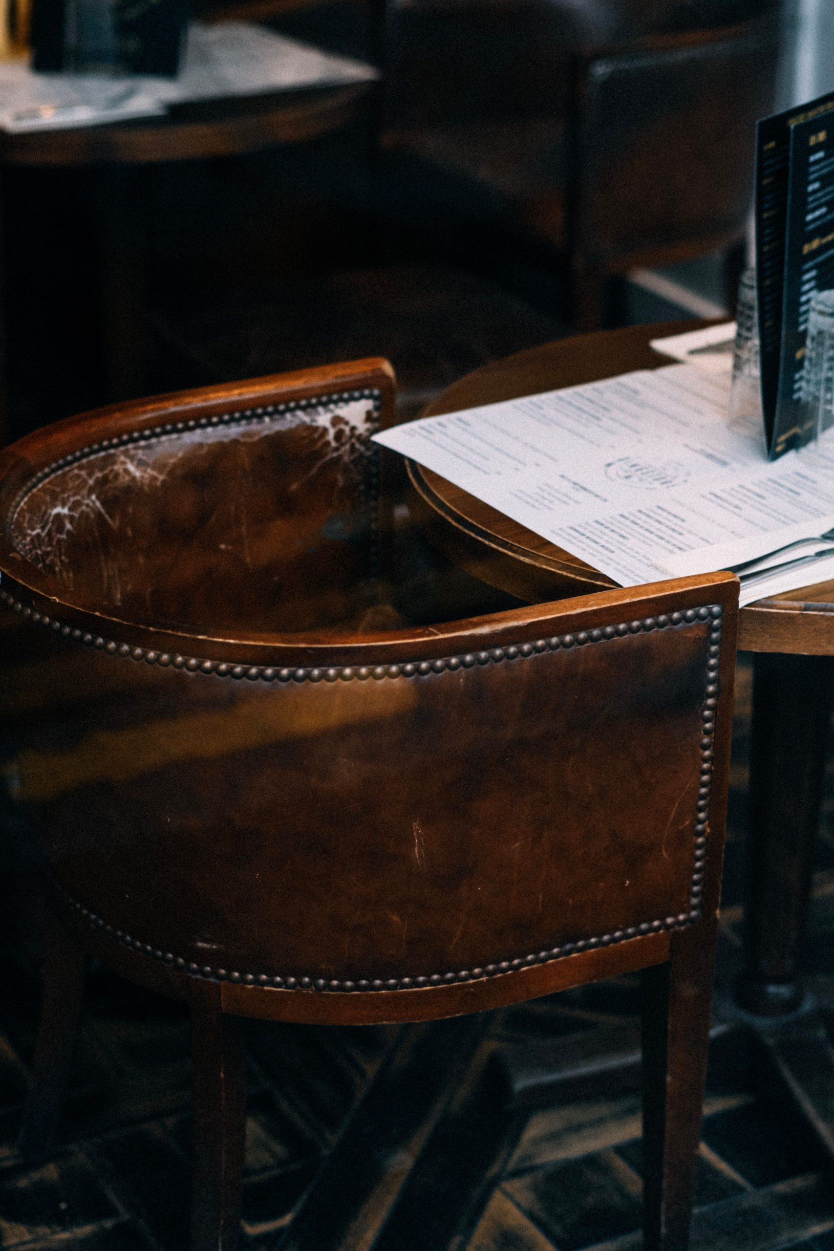 A classic brown leather chair and table setup in a cozy café setting with menus displayed.