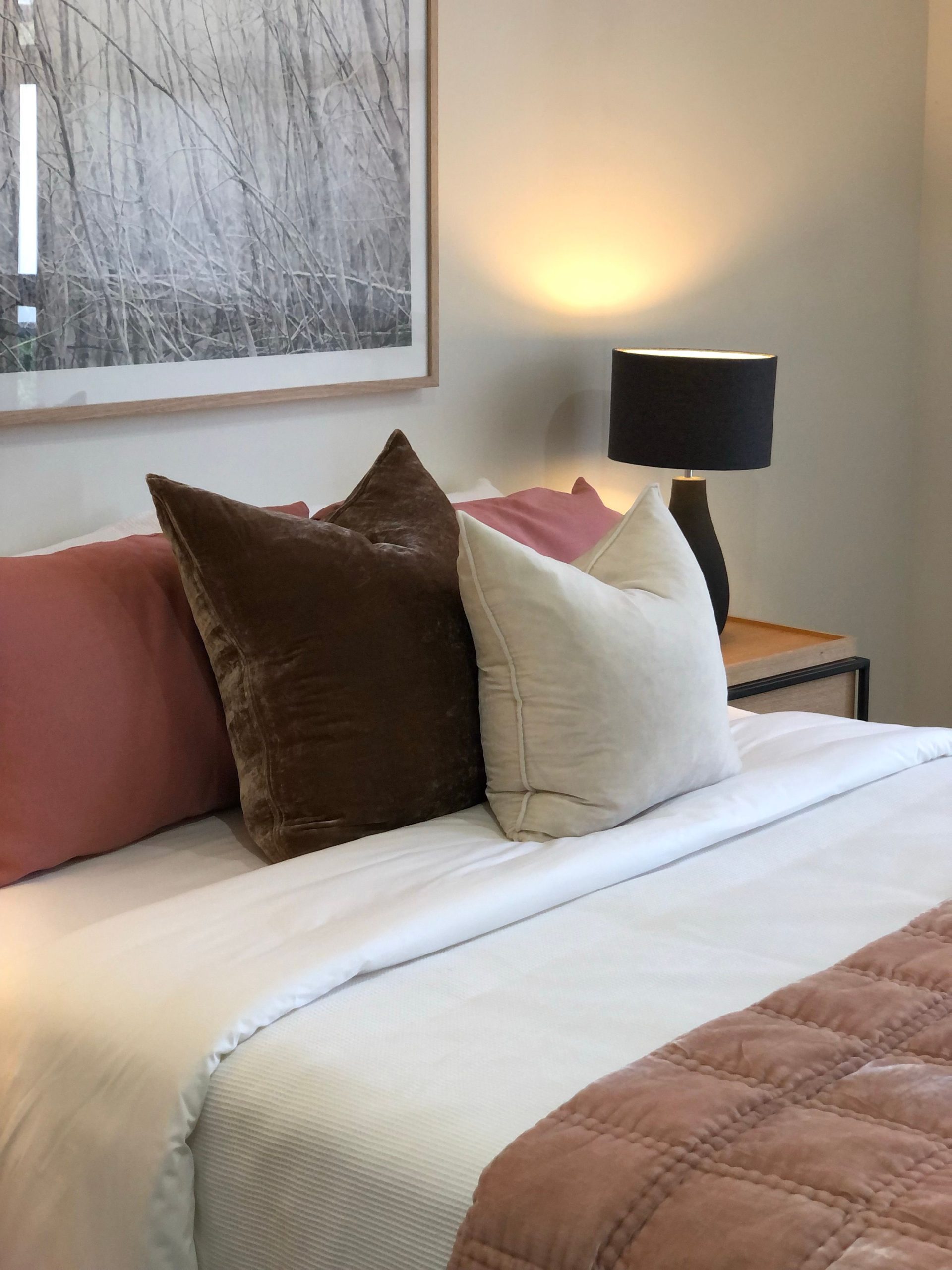 A cozy and stylish bedroom featuring elegant pillows and soft lighting, creating a warm atmosphere.