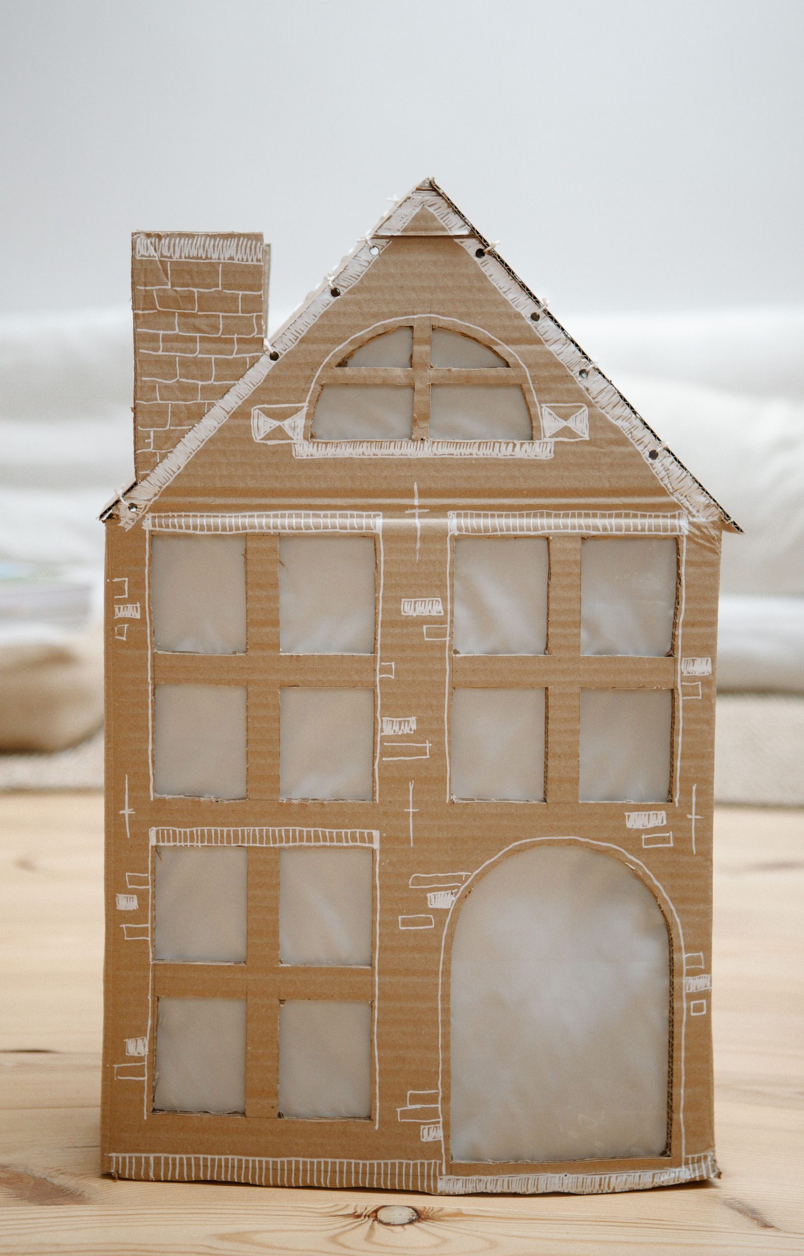 A detailed cardboard Christmas house model with decorative elements, perfect for holiday décor.