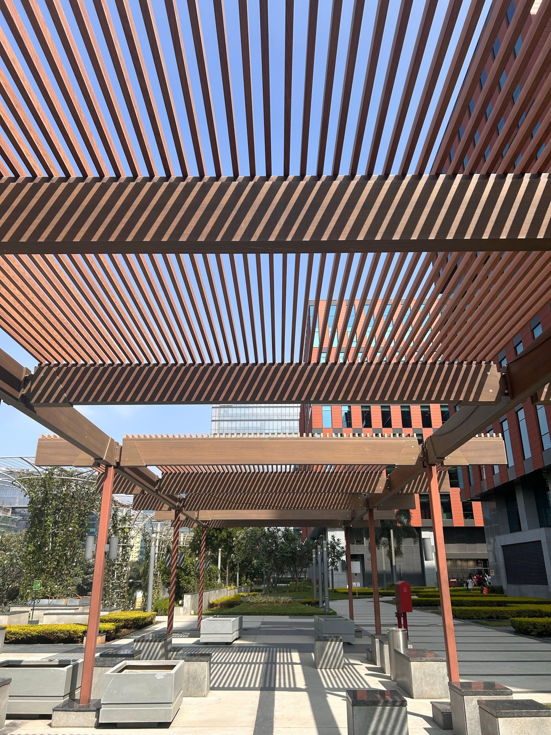 A dynamic outdoor space featuring a wooden pergola casting shadows on a sunny day.