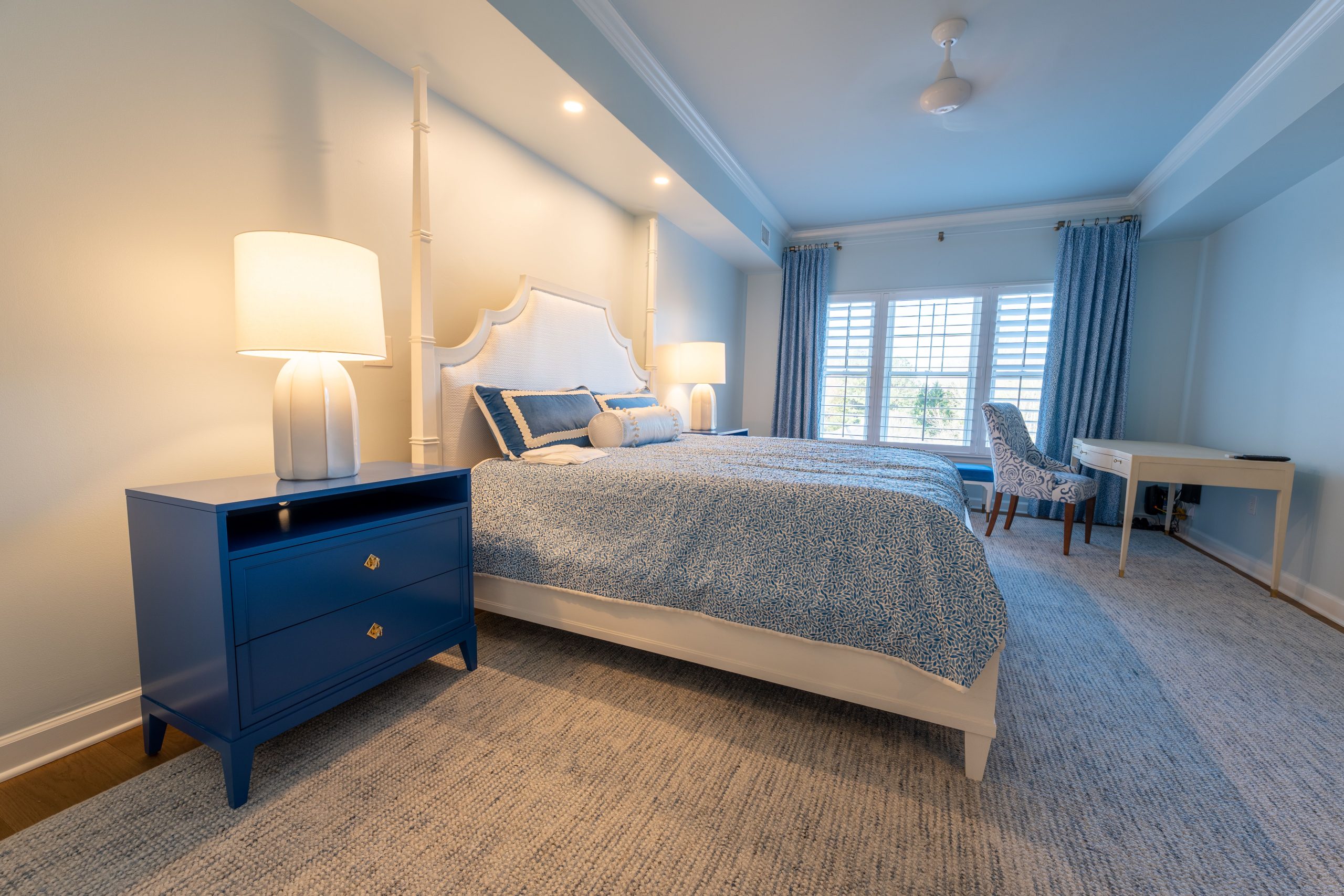 A luxurious bedroom with blue and white decor, featuring a large bed and stylish furniture.