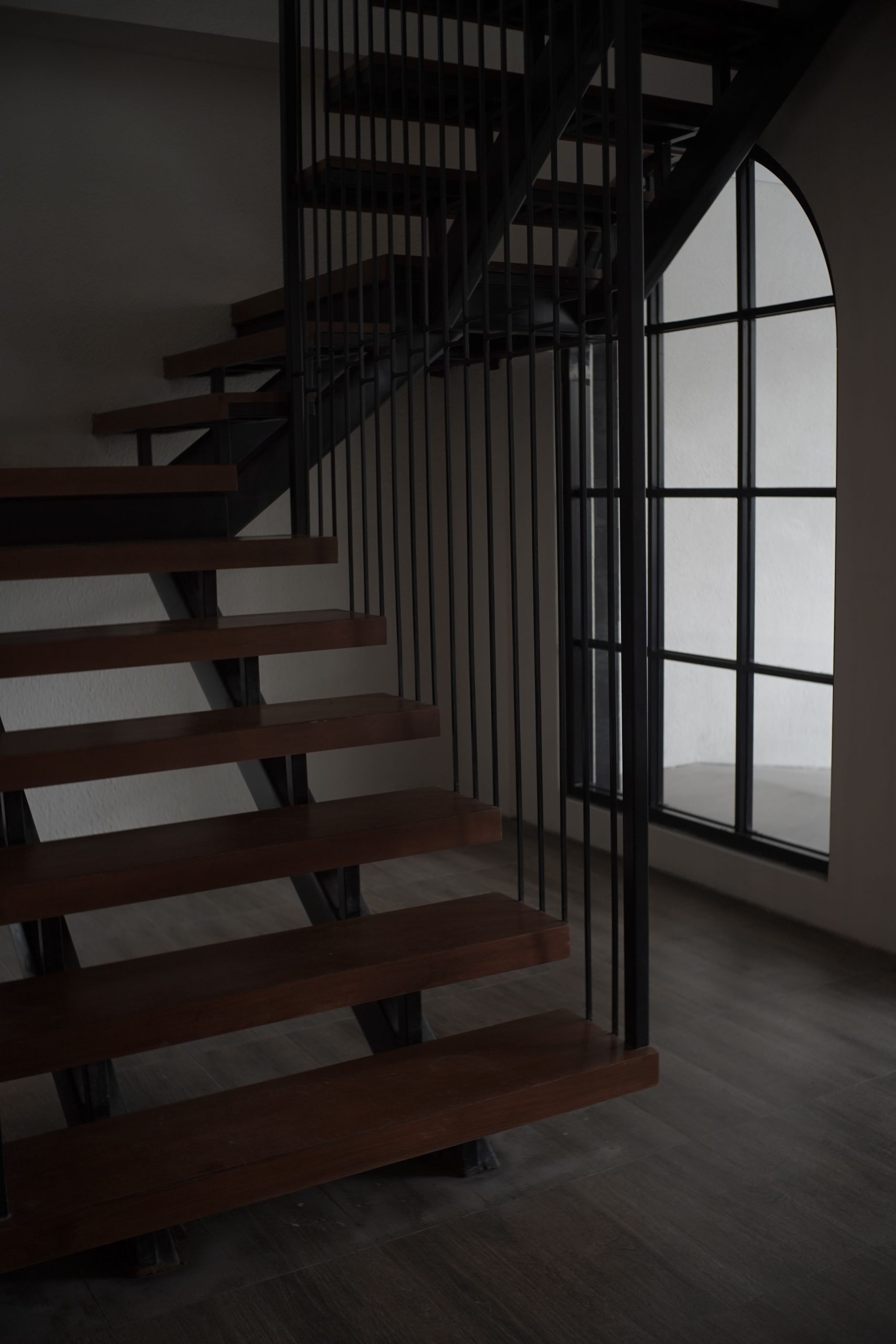 A modern, wooden staircase in a minimalist indoor setting with natural lighting.